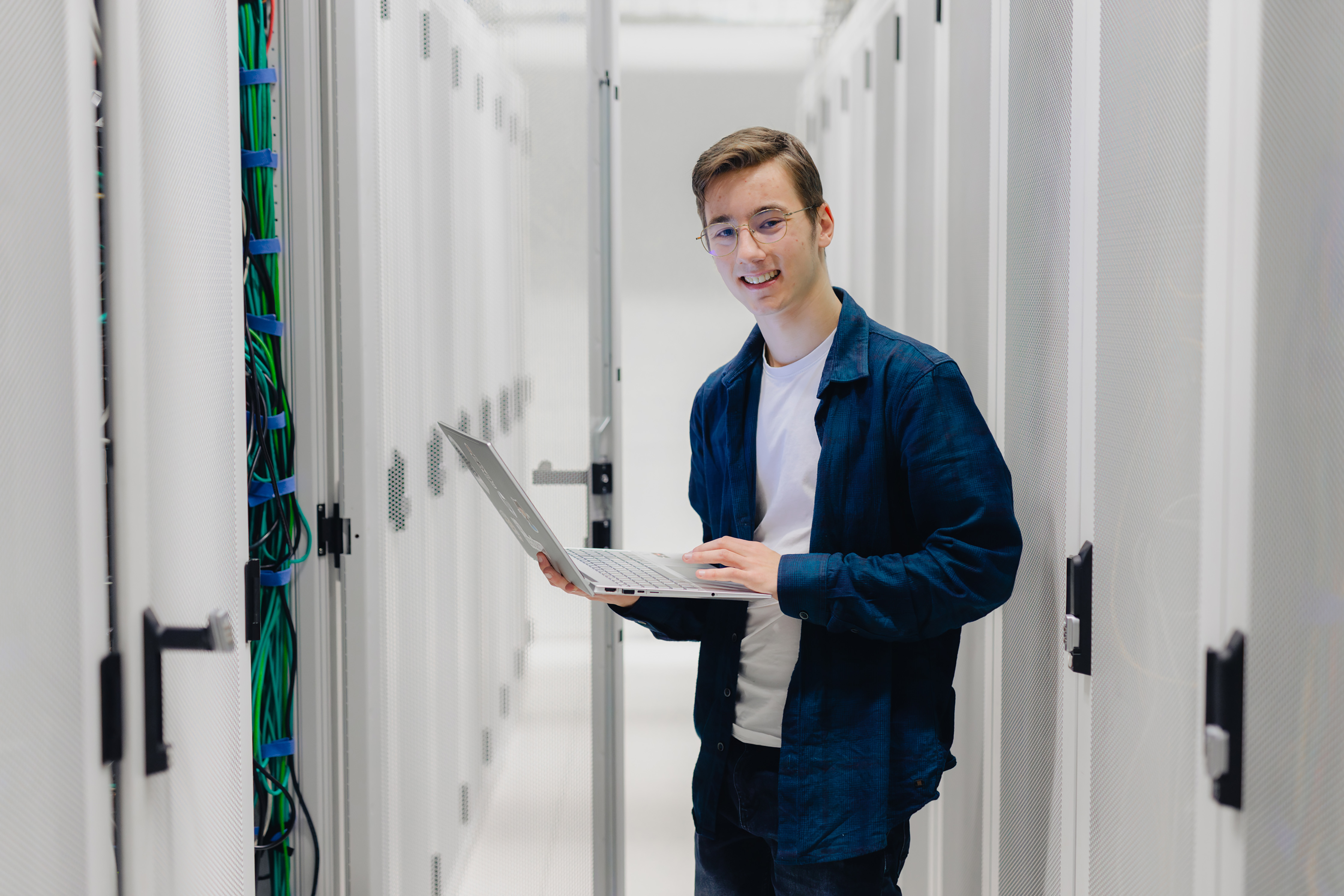 Student gebruikt laptop in datacenter tijdens studie en ondernemerschap.