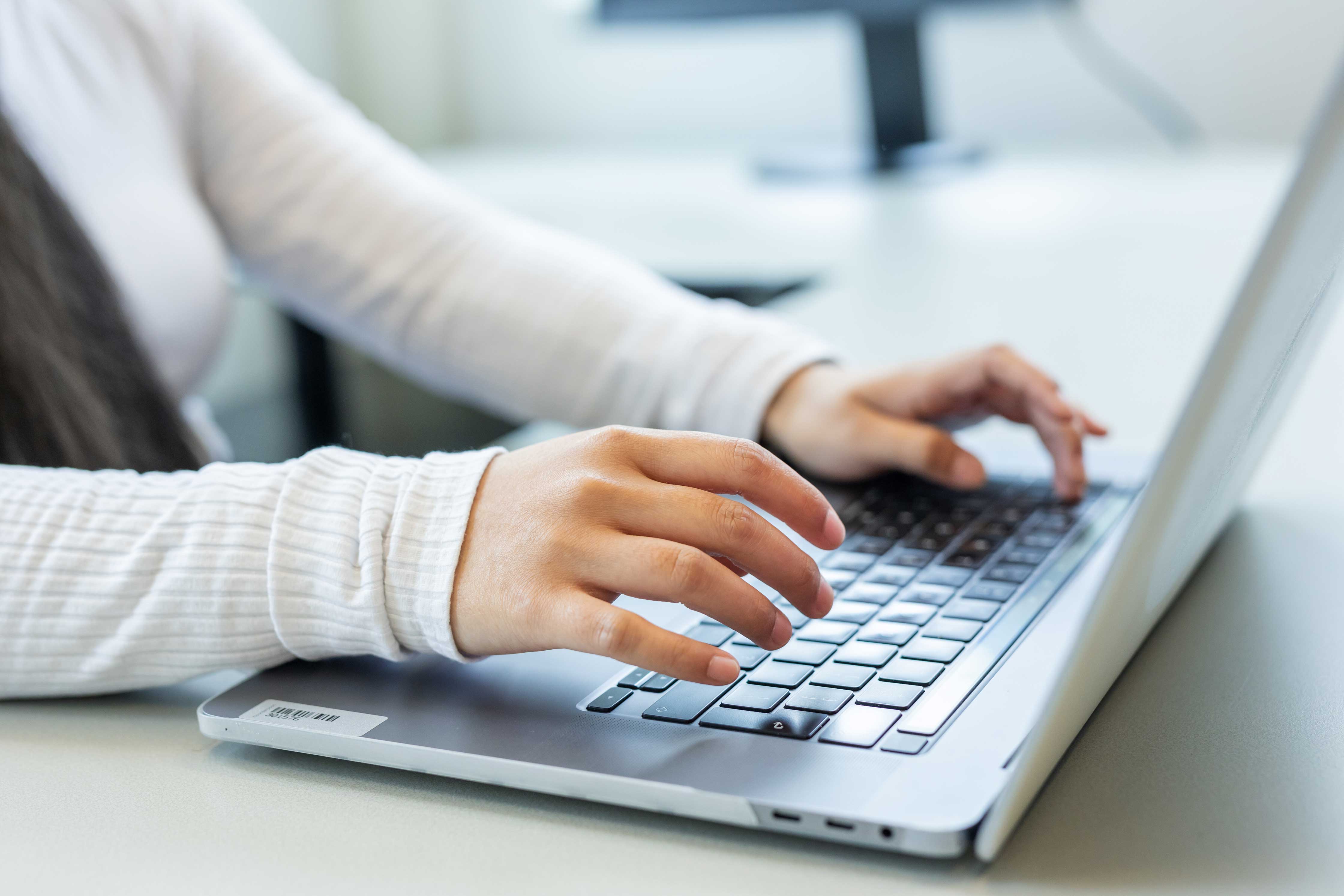 Iemand werkt geconcentreerd op een laptop, passend bij een ICT-opleiding of werksituatie in het MBO.