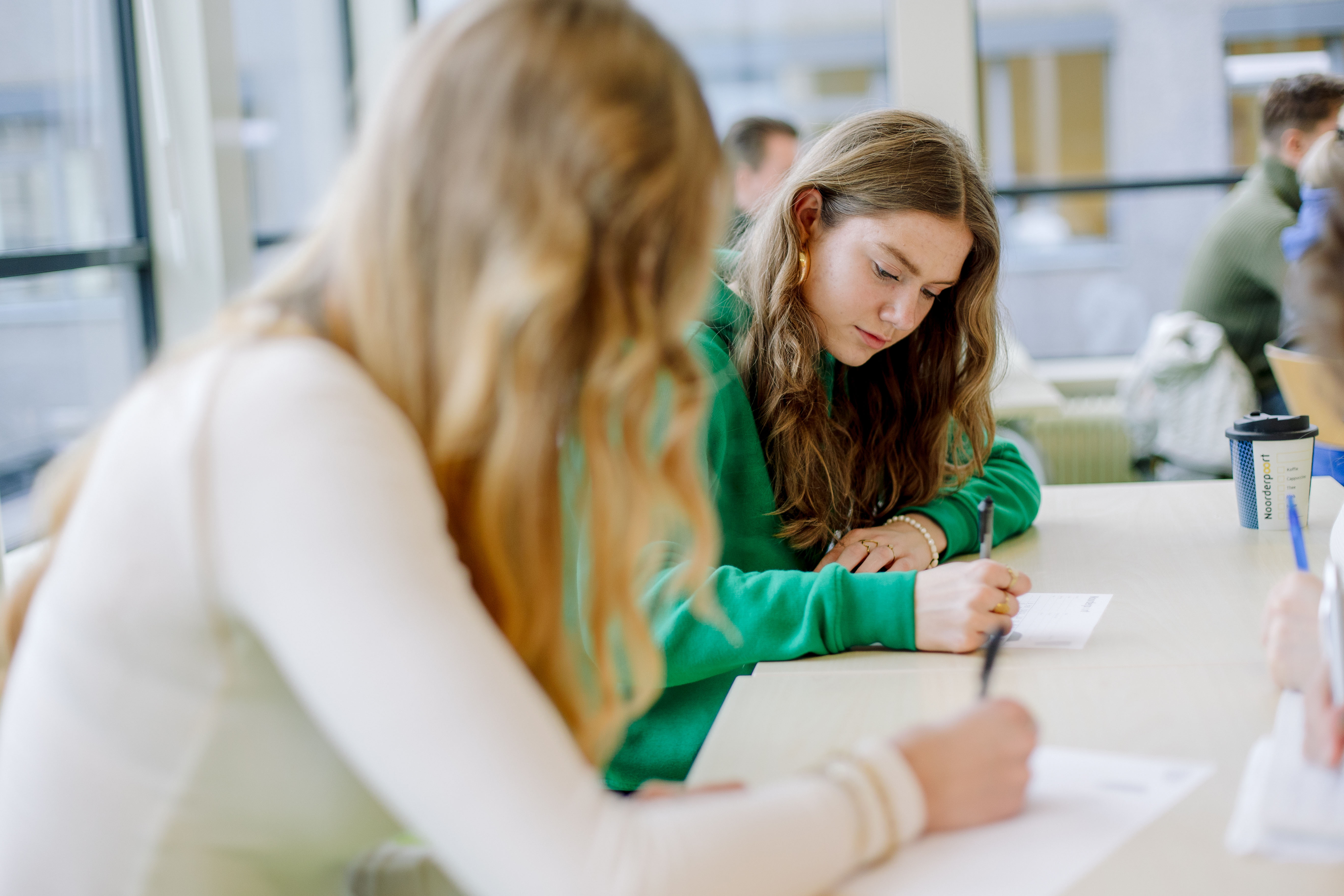 Toekomstige student verdiept zich in schriftelijke opdrachten tijdens meeloopdag bij Noorderpoort