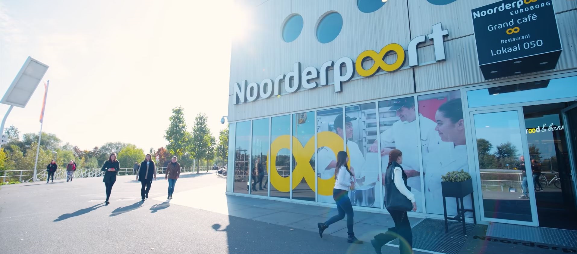 Voorzijde van Noorderpoort Boumaboulevard 113 in Groningen met studenten die het gebouw betreden.