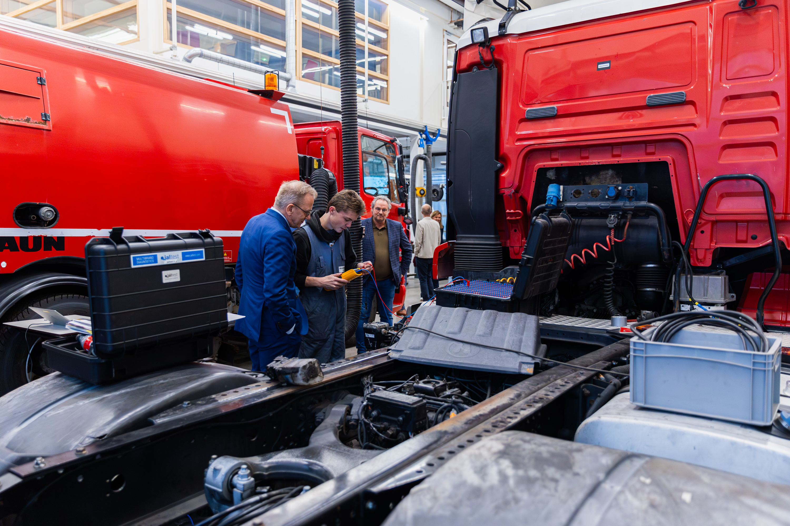 Studenten en een docent onderzoeken technische onderdelen van een vrachtwagen tijdens een mobiliteitsproject.