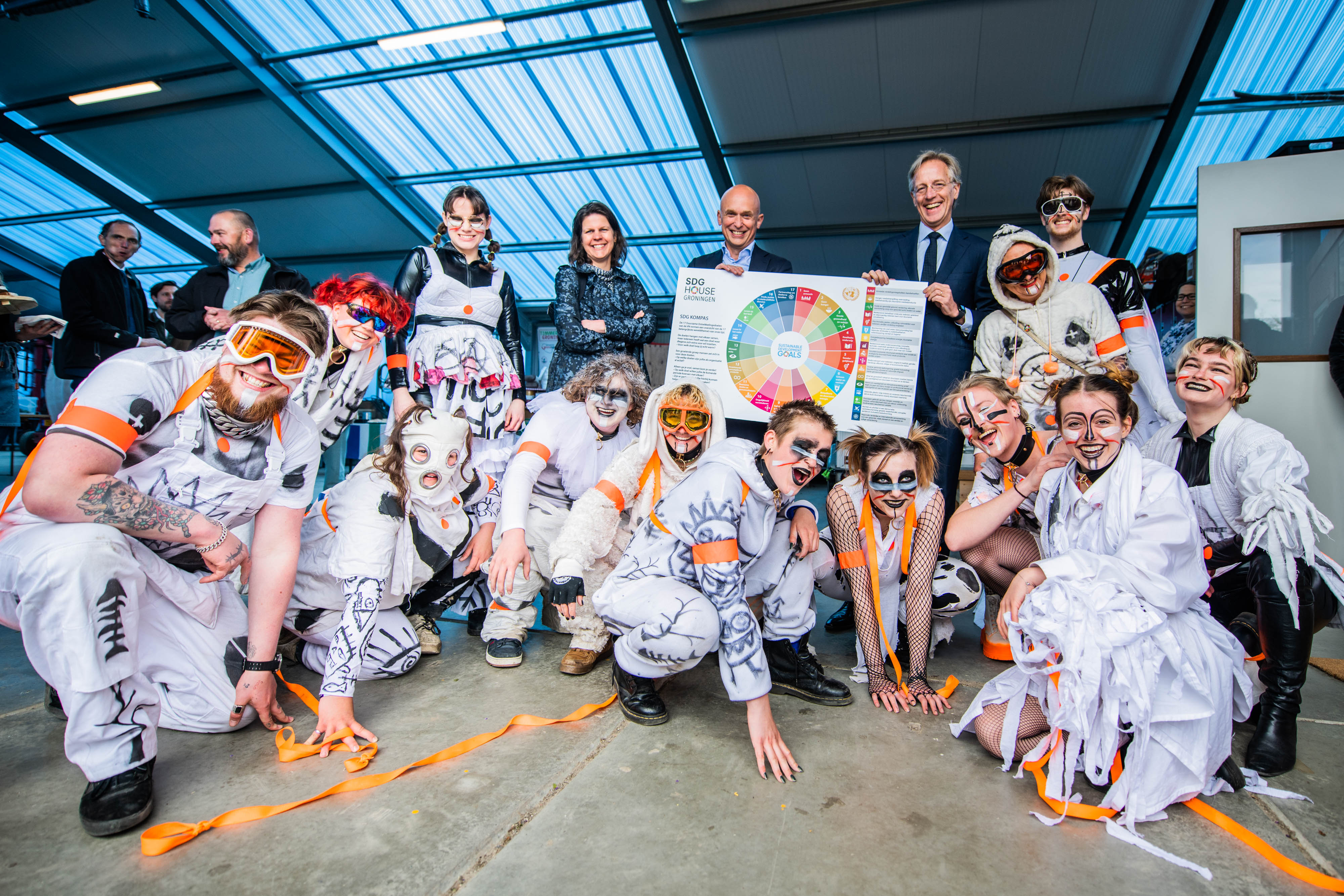 Groep studenten en docenten presenteren een duurzaamheidsmodel tijdens bezoek van minister Dijkgraaf.