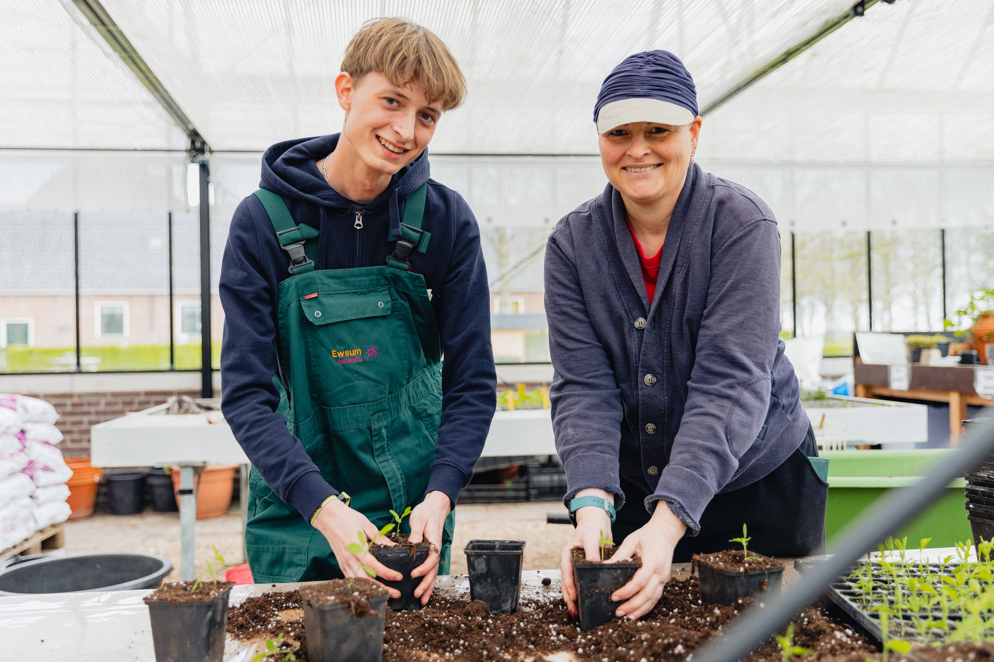 Twee stagiairs planten jonge planten in potten tijdens een praktijkdag bij WerkPro Op Ewsum.