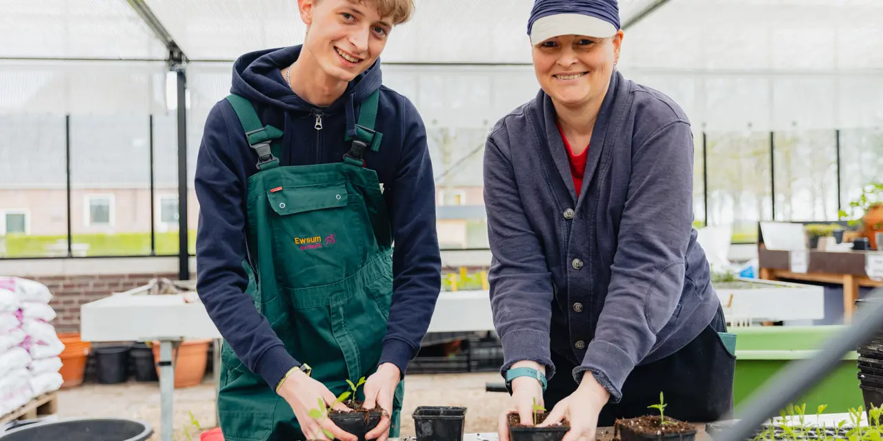 Twee stagiairs planten jonge planten in potten tijdens een praktijkdag bij WerkPro Op Ewsum.