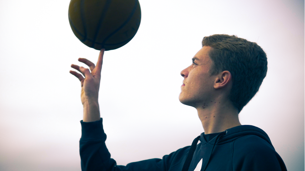 Student oefent met basketball, gericht op het balanceren van de bal op één vinger tijdens training