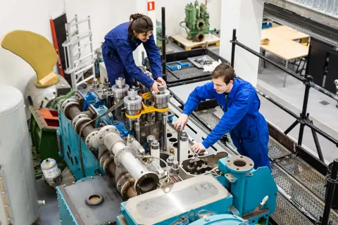 Technische studenten werken samen aan het onderhoud van een complexe maritieme machine
