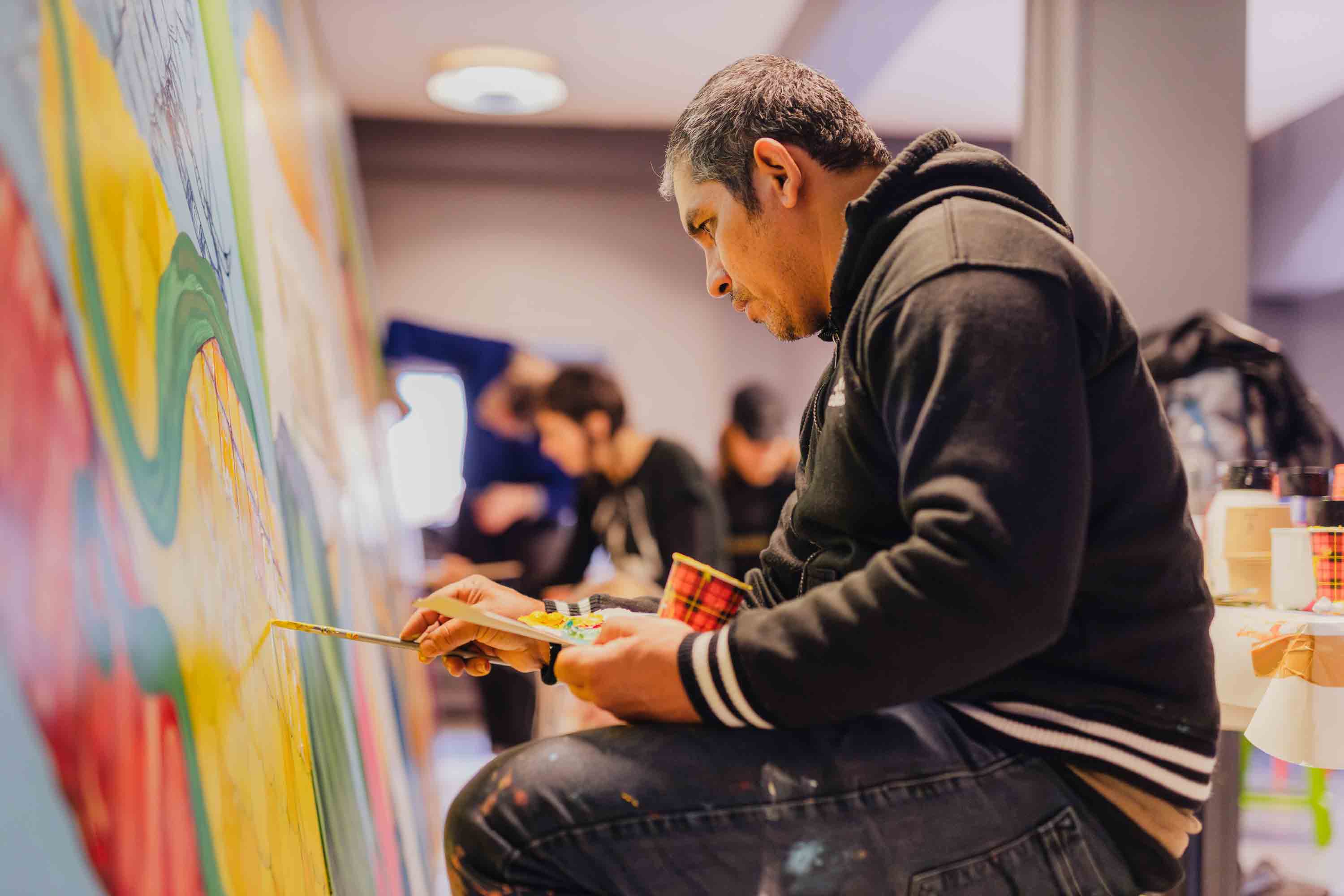 Student werkt geconcentreerd aan een watergerelateerde muurschildering tijdens een creatief kunstproject