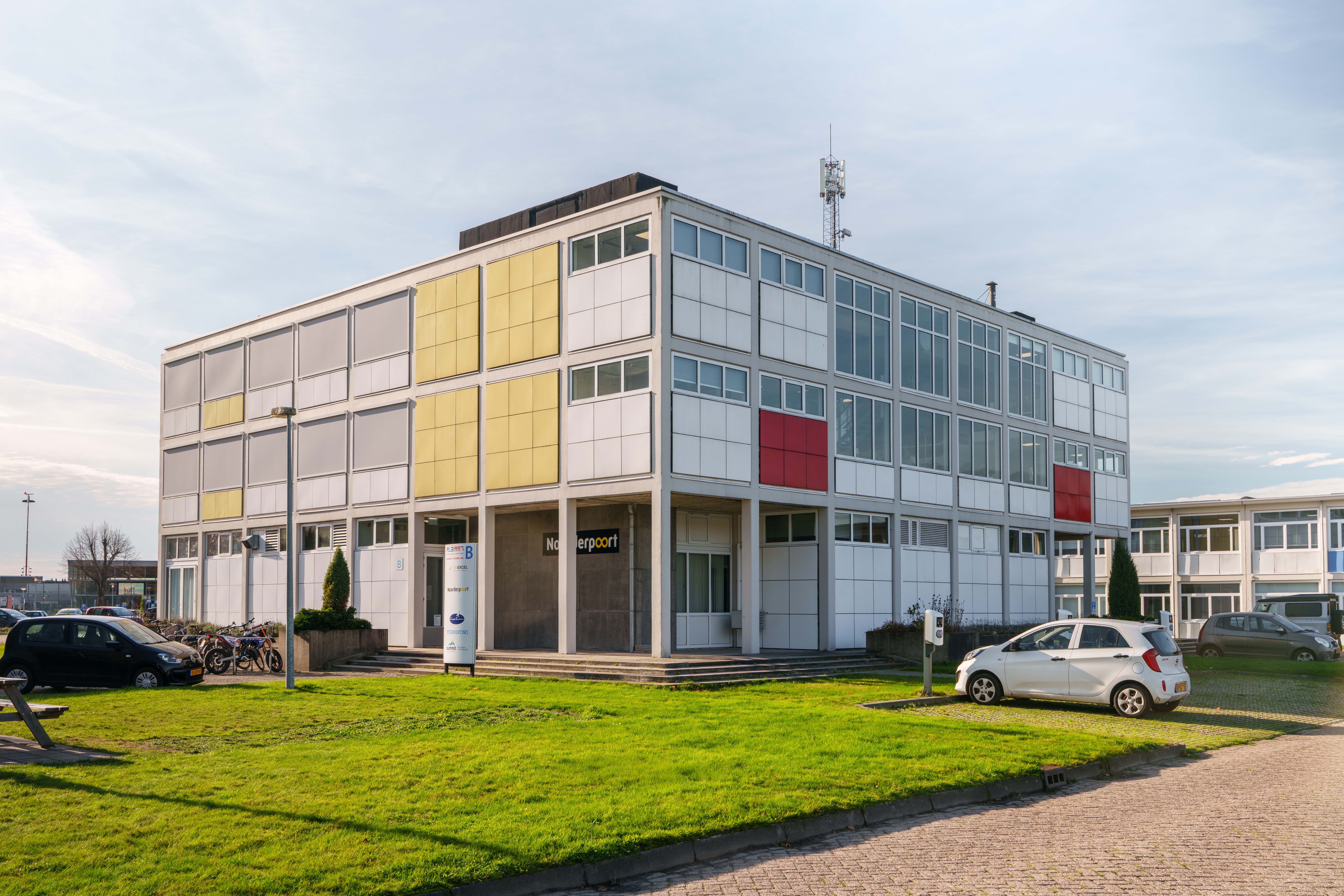 Onderwijsgebouw van Noorderpoort aan Burgemeester J.G. Legroweg in Eelde met groene omgeving en voertuigen.