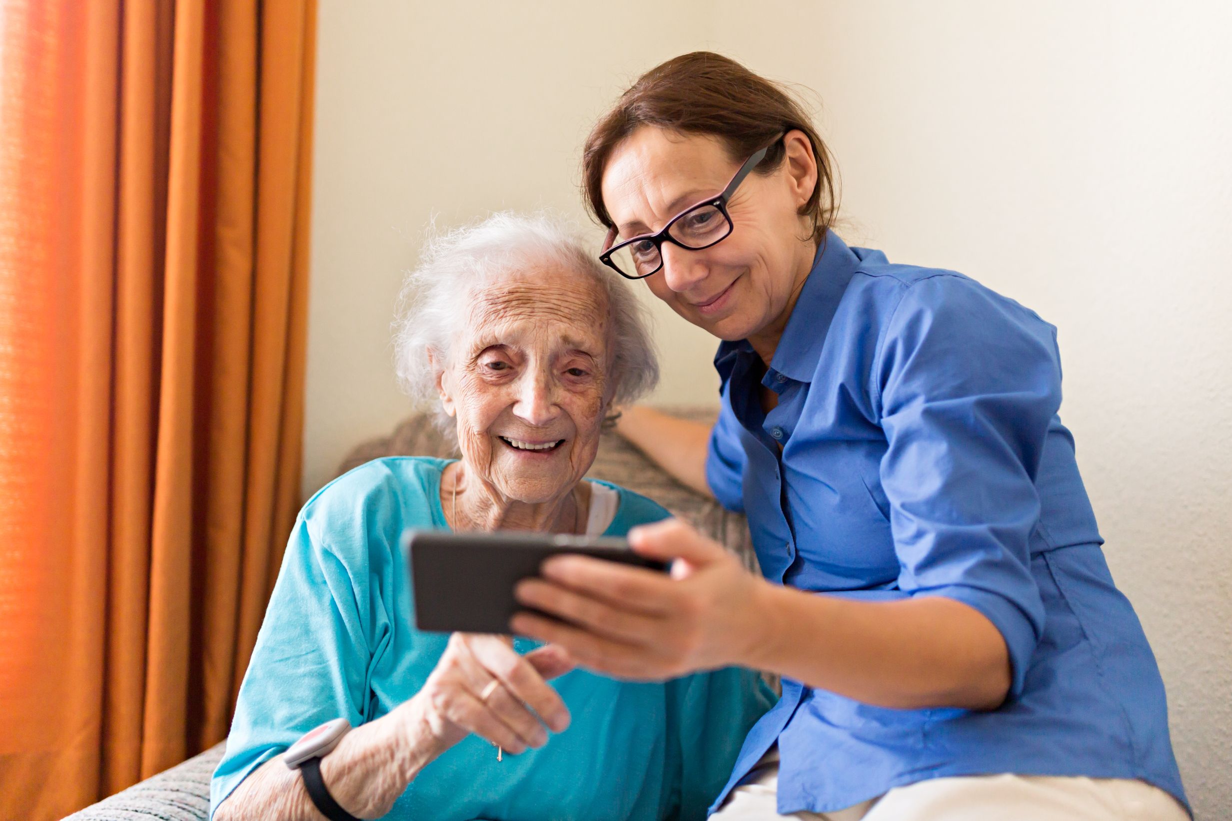 Zorgprofessional toont technische toepassing op smartphone aan oudere zorgvrager.