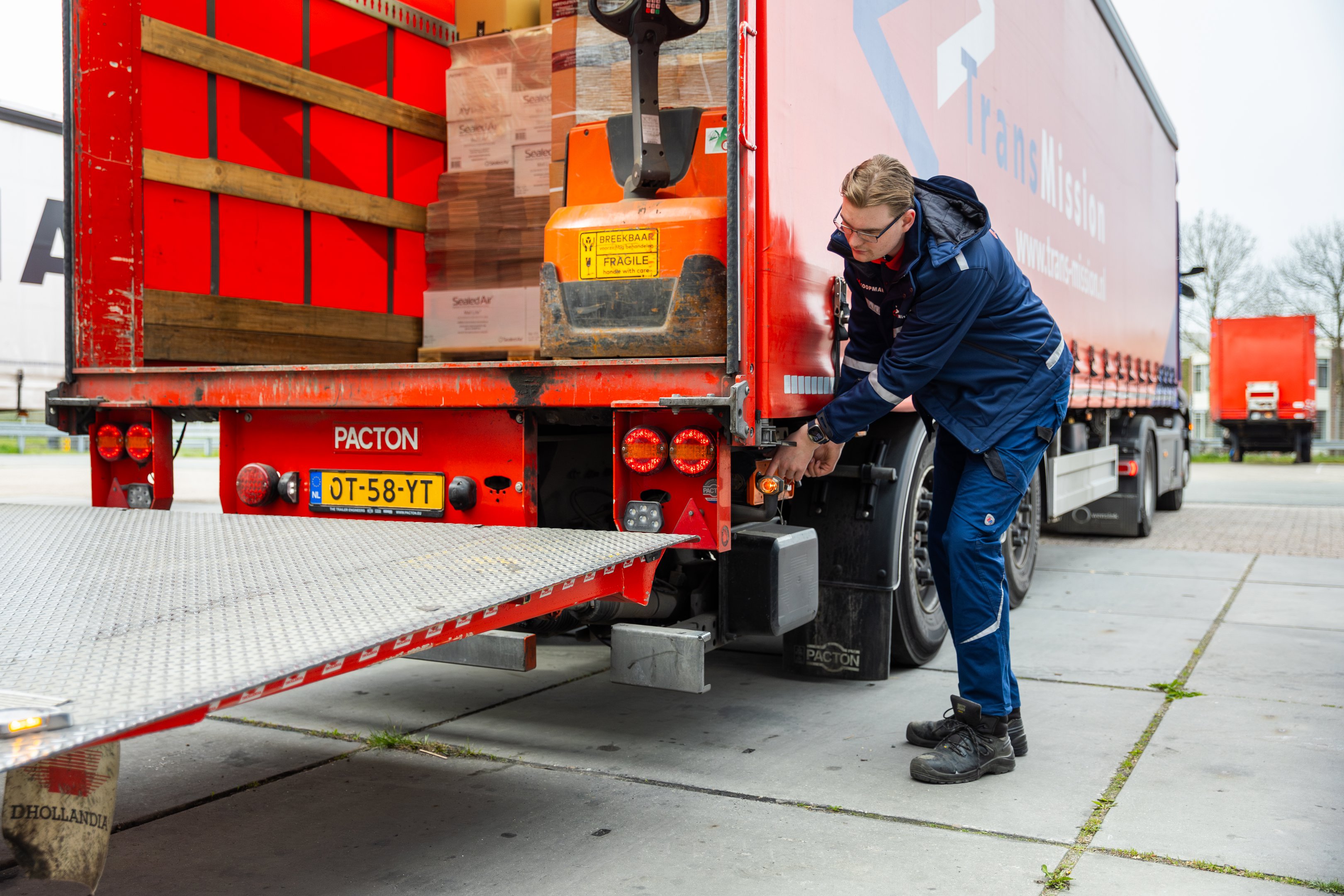 Student voert controle uit aan achterkant van een vrachtwagen tijdens logistieke stage.