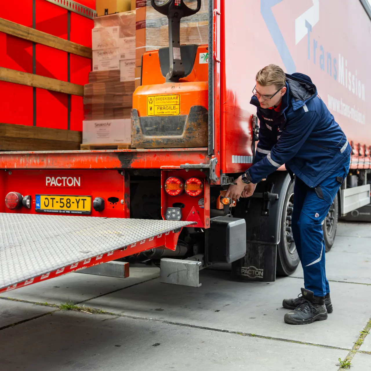Student voert controle uit aan achterkant van een vrachtwagen tijdens logistieke stage.