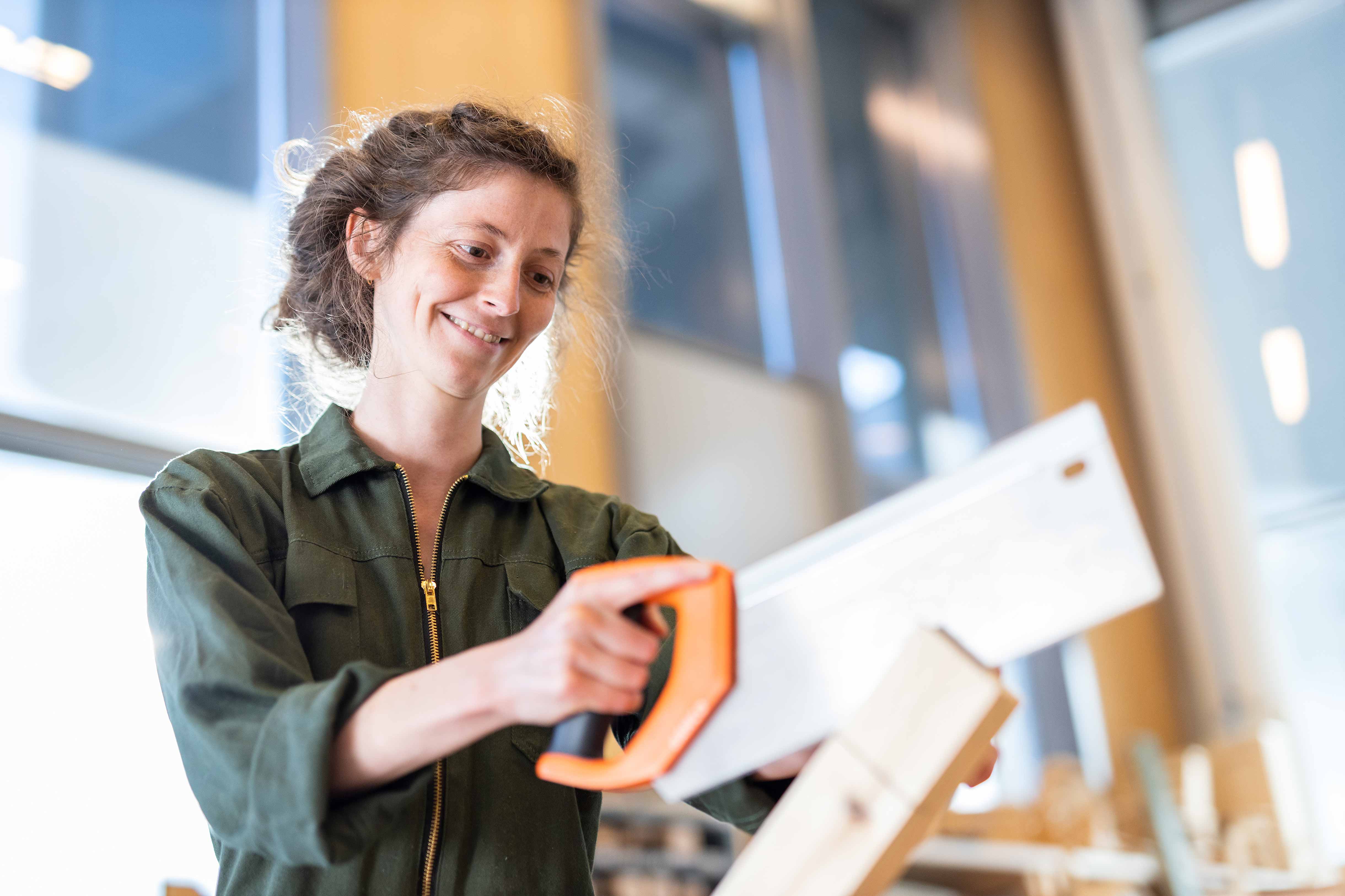 Student in praktijkruimte oefent met handzaag op hout in een mbo-opleiding techniek