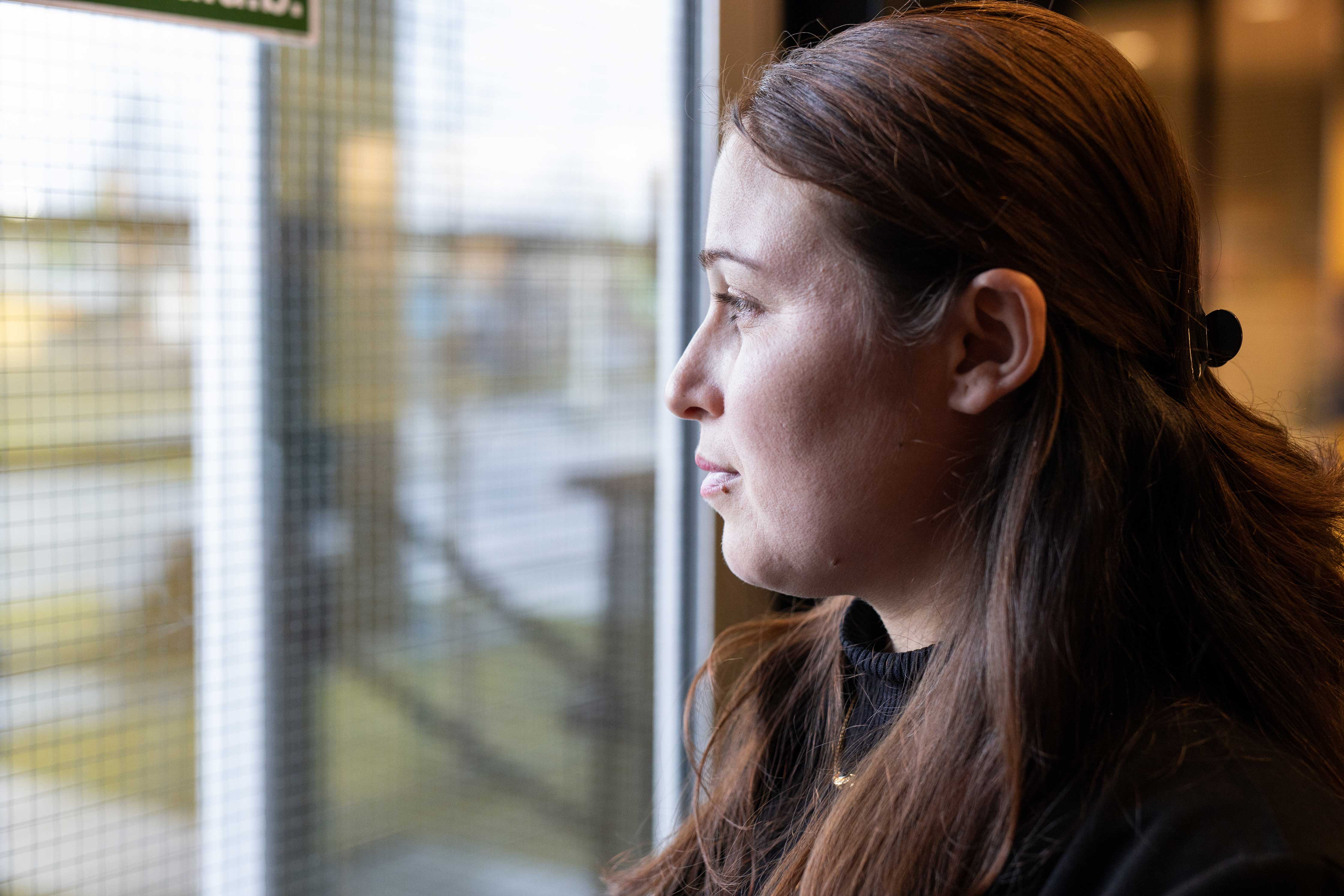 Student kijkt nadenkend door raam, symbool voor nieuwe start en integratie in Nederland