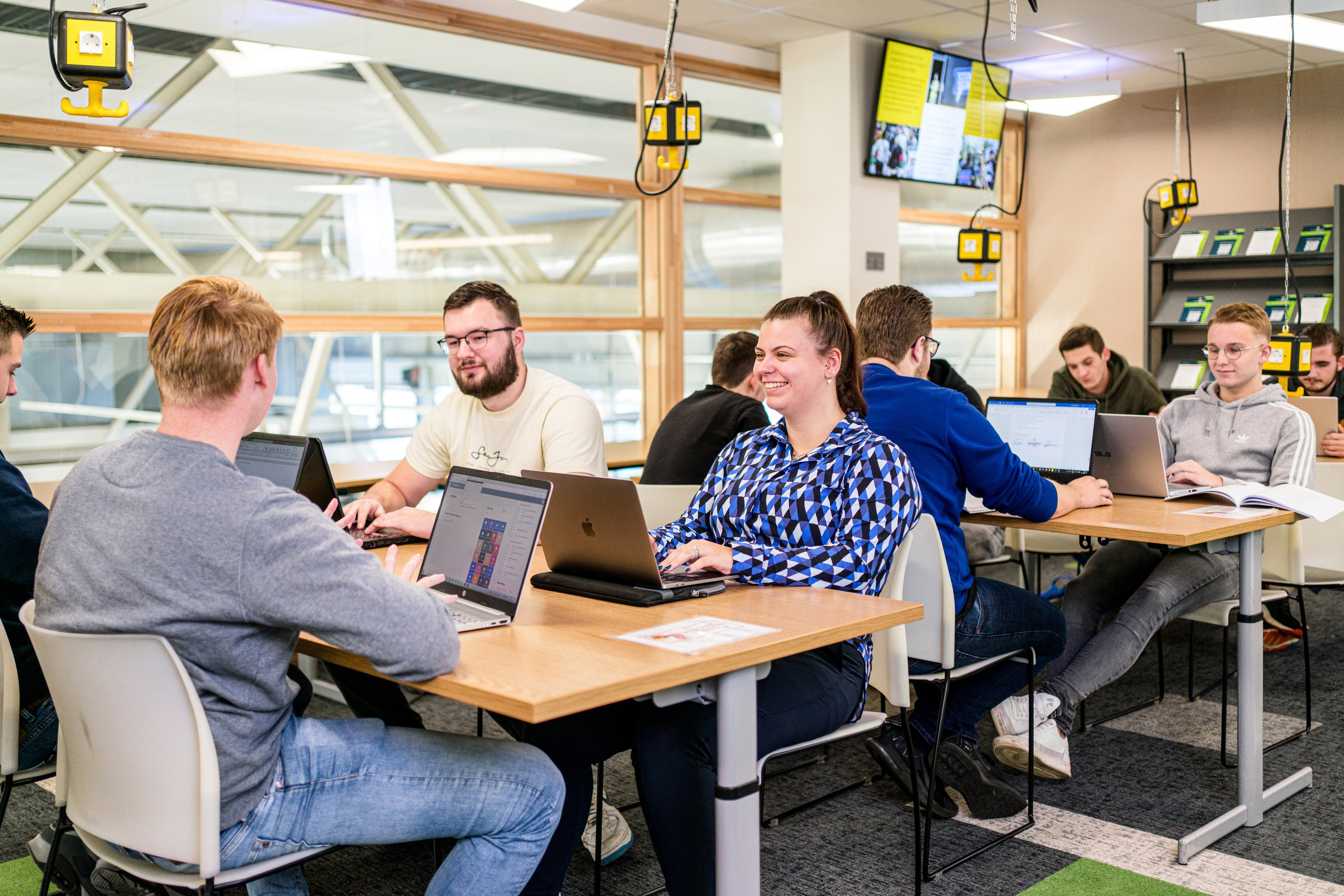 Studenten werken samen aan laptops in een studieomgeving gericht op digitaal burgerschap.
