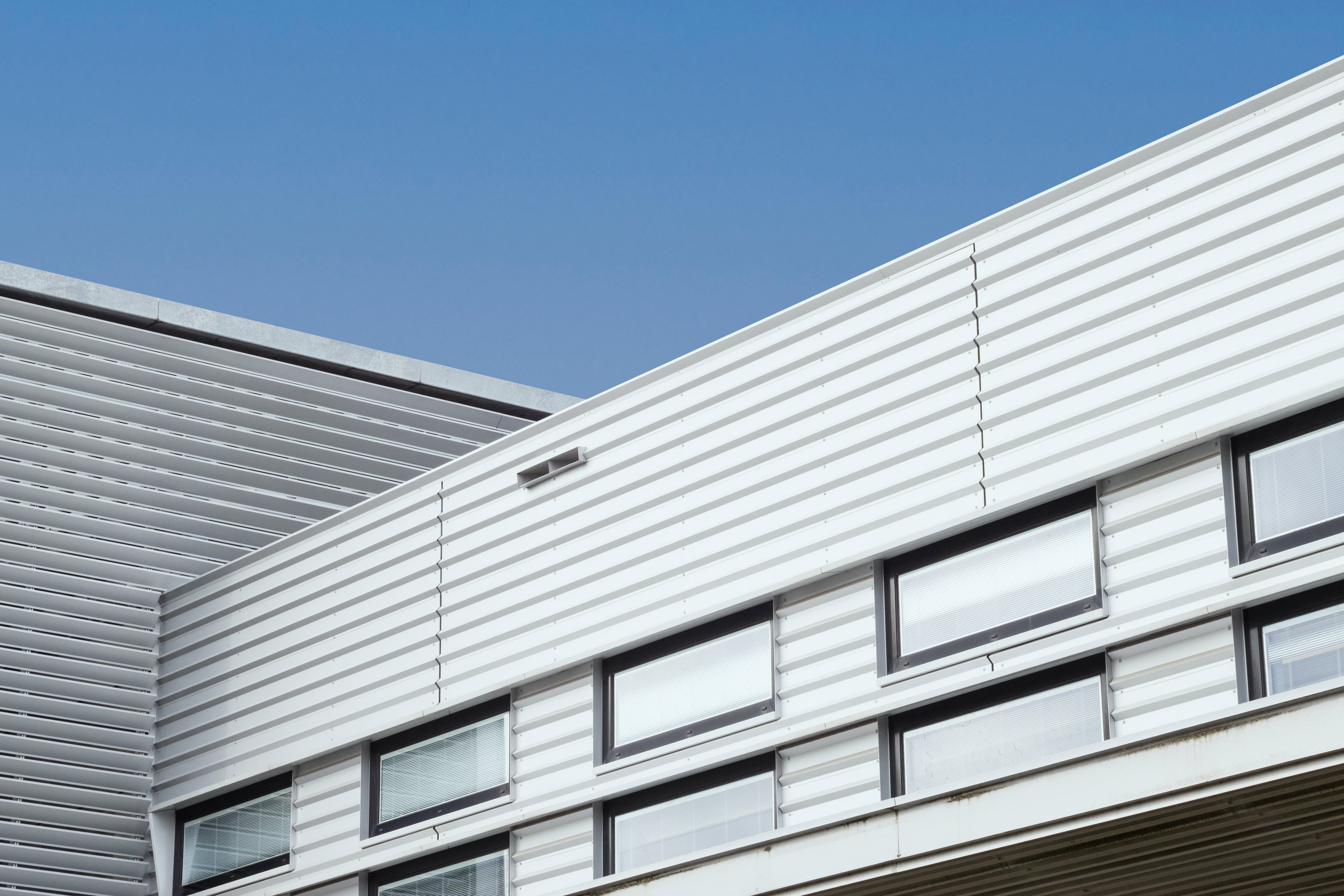 Moderne gevel van een onderwijsgebouw met horizontale panelen en ramen die daglicht binnenlaten