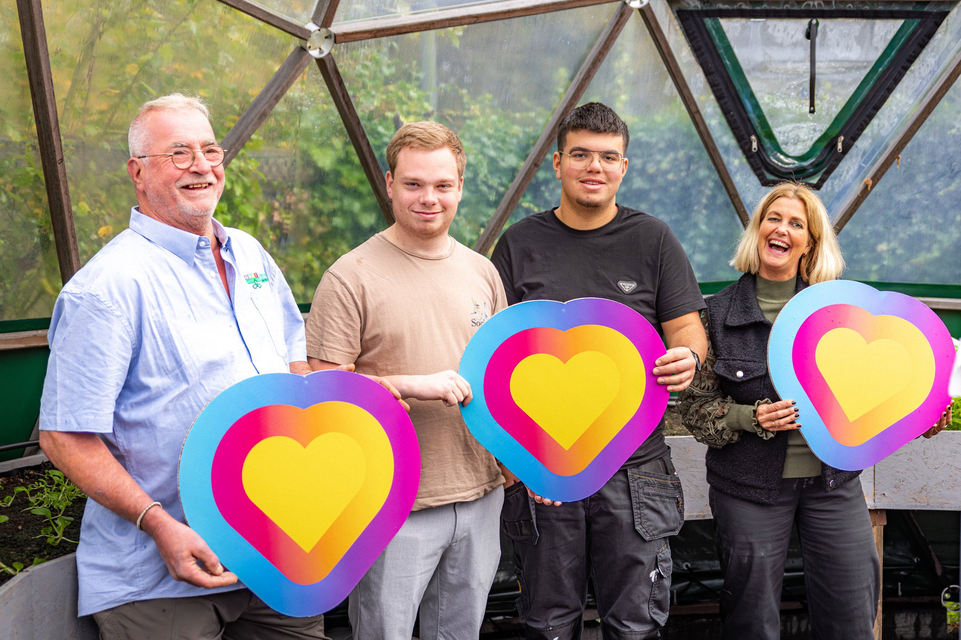Vier betrokken personen bij De Dome Stadskanaal houden kleurrijke symbolen vast als teken van verbondenheid