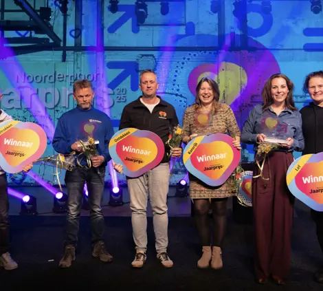 Zes winnaars van de Noorderpoort Jaarprijs 2025 poseren samen met hun bekers en uitreikingsborden
