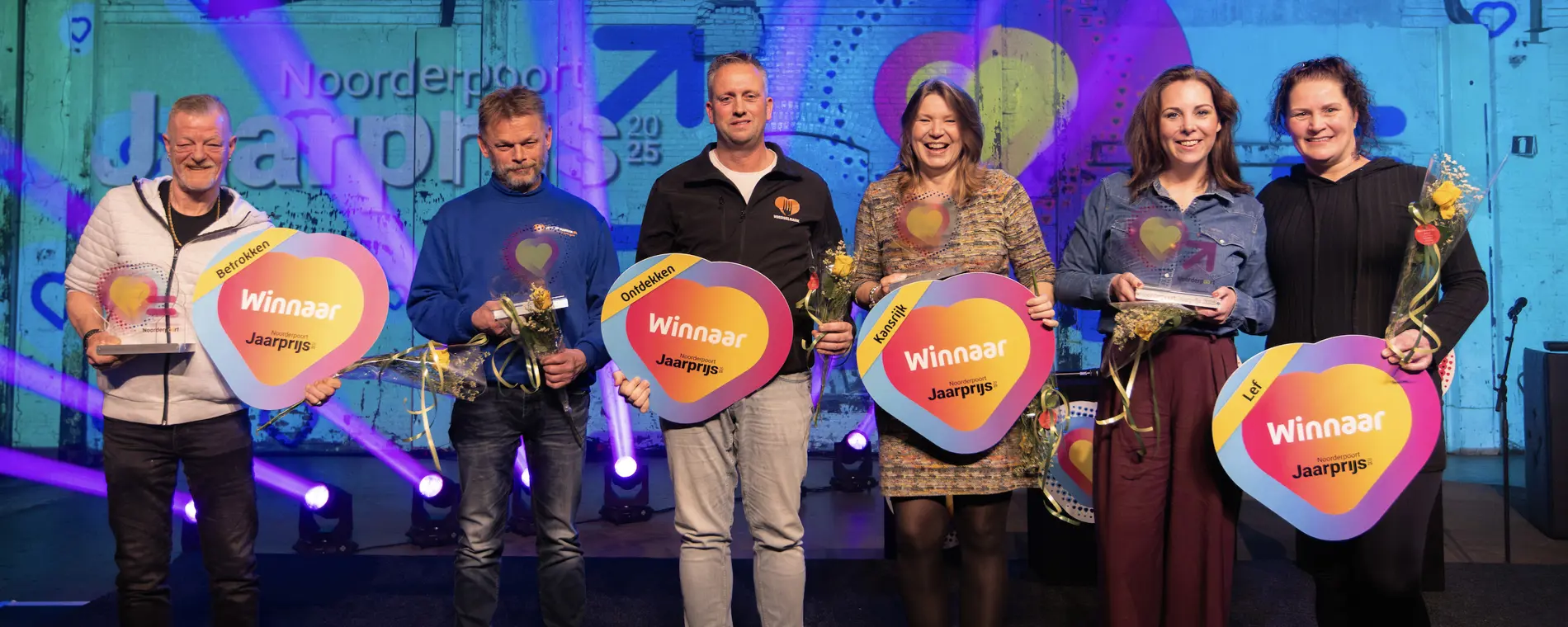 Zes winnaars van de Noorderpoort Jaarprijs 2025 poseren samen met hun bekers en uitreikingsborden
