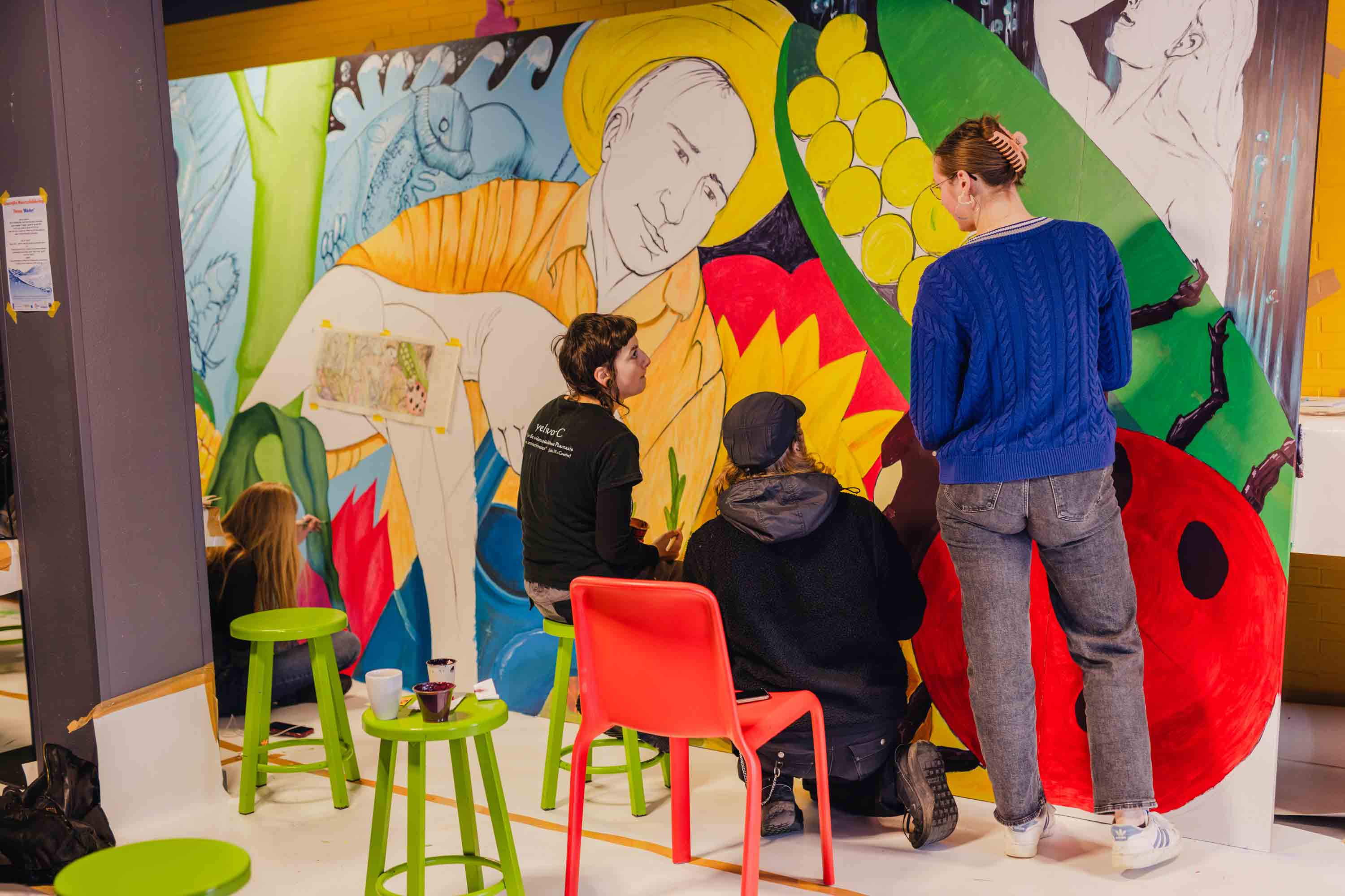 Studenten werken samen aan een kleurrijke muurschildering met natuur- en waterthema ter bewustwording.