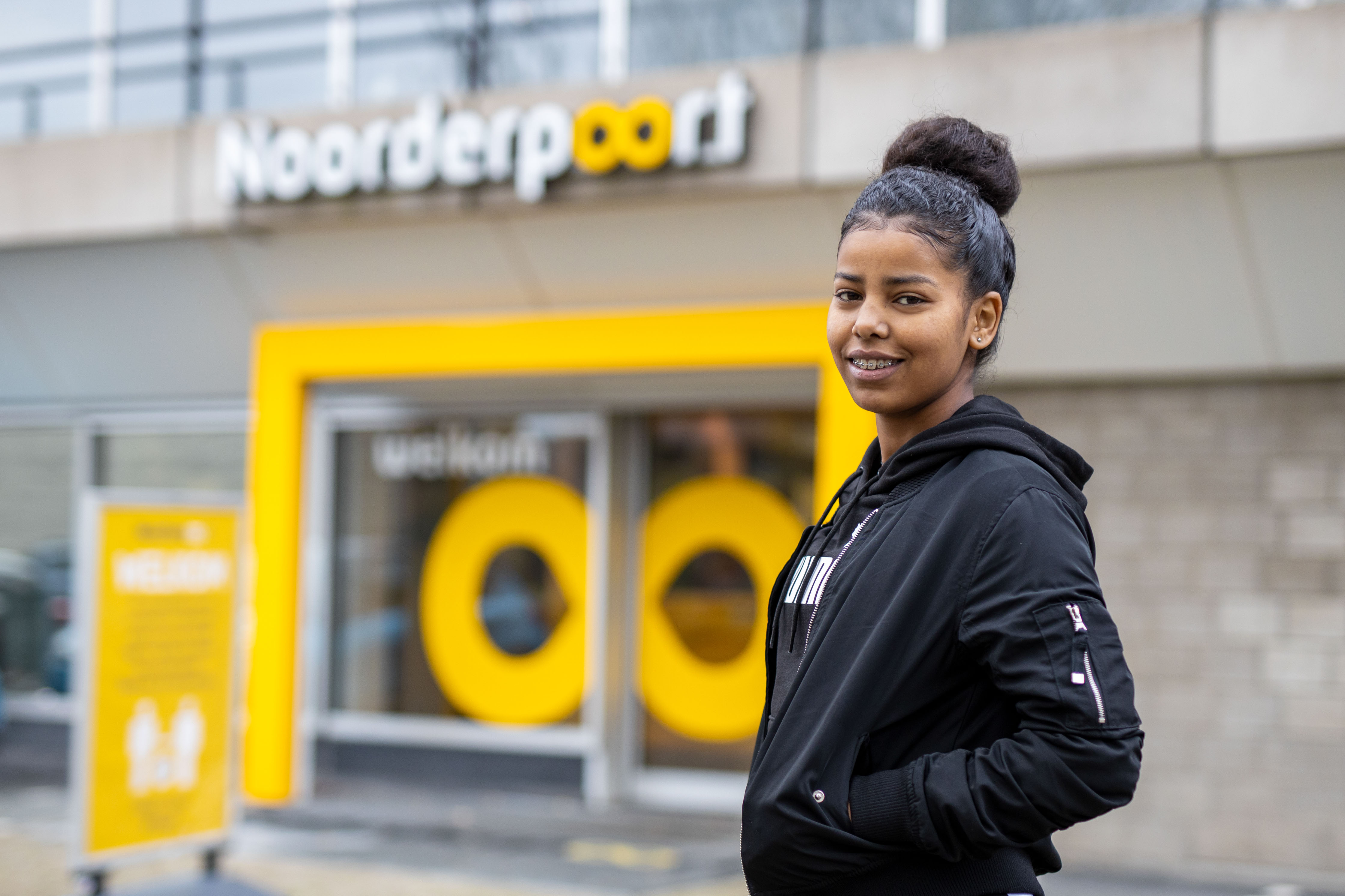 Toekomstige student staat voor de ingang van Noorderpoort, voorbereidend op beroepsopleiding in Noord-Nederland.