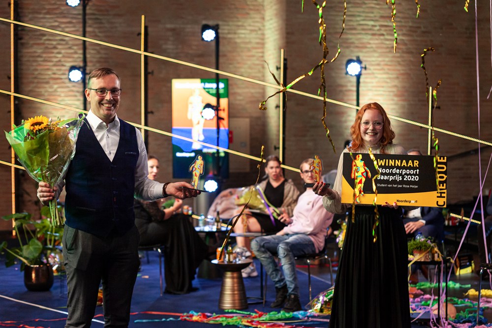 Student ontvangt de Noorderpoort Jaarprijs 2020 tijdens een feestelijke uitreiking, met een docent aan haar zijde.