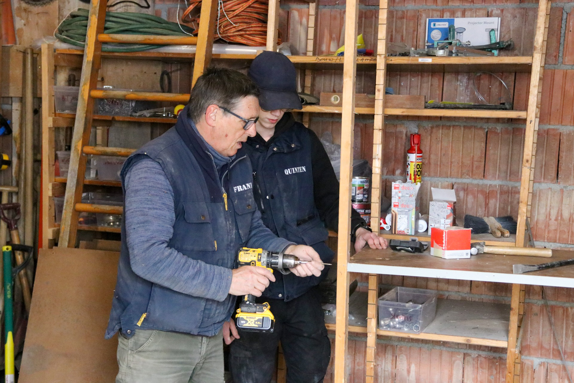 Mbo-student en docent werken samen met boormachine aan houtconstructie in praktijkruimte
