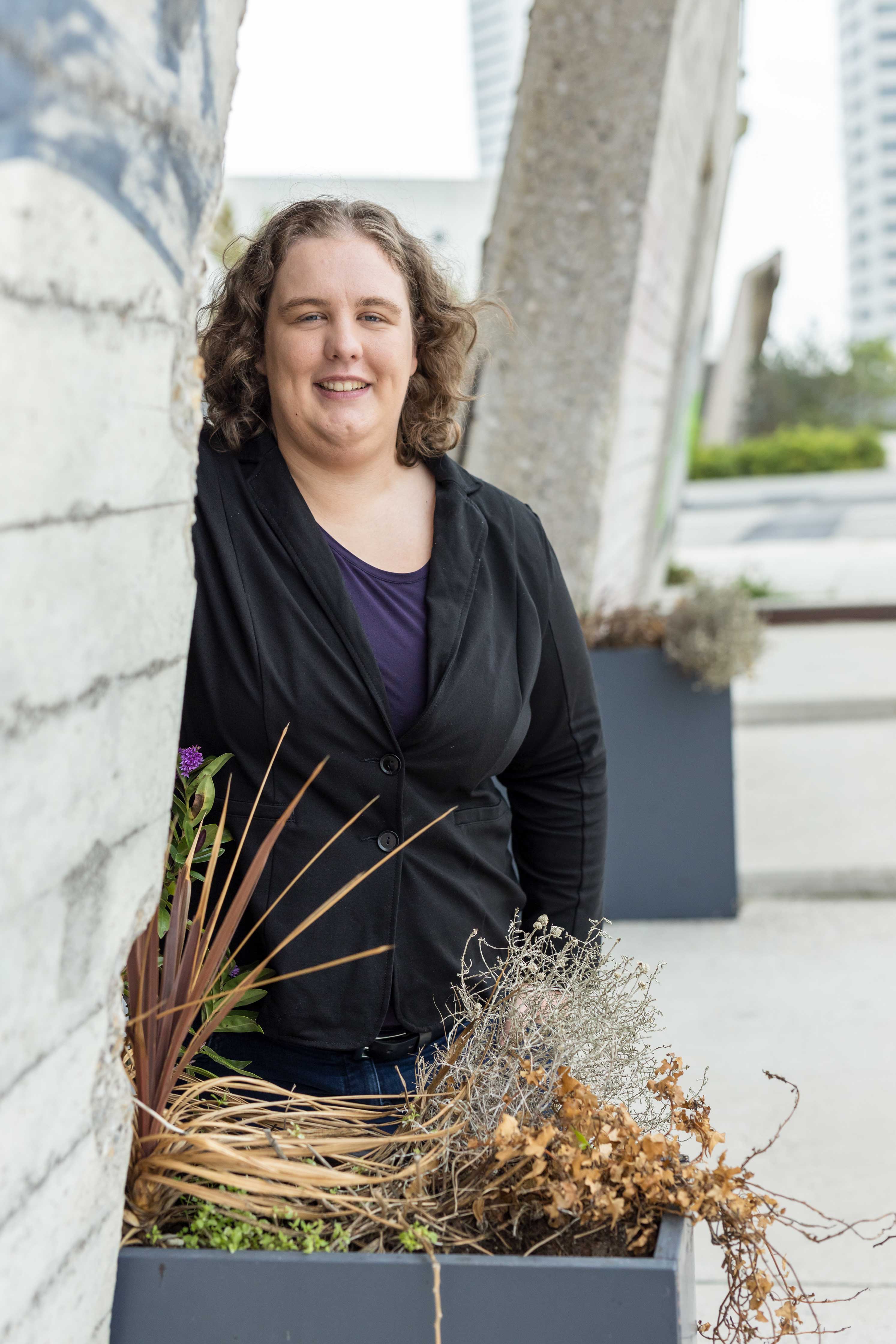 Persoon leunt tegen buitenmuur met stedelijke achtergrond, passend bij diversiteitsverhaal over acceptatie