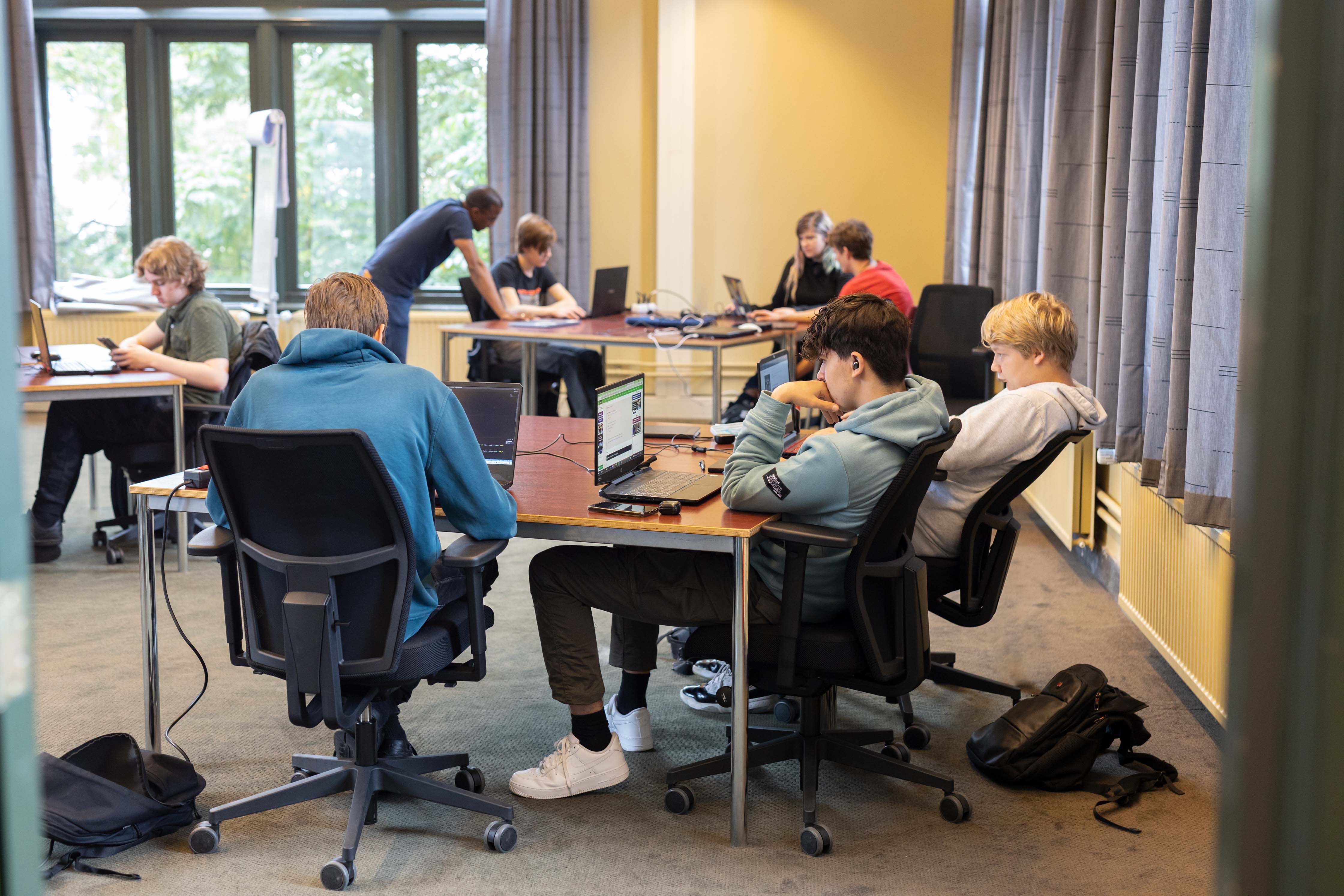 Studenten werken samen aan programma's tijdens een praktijkgerichte ICT-opleiding bij Noorderpoort.