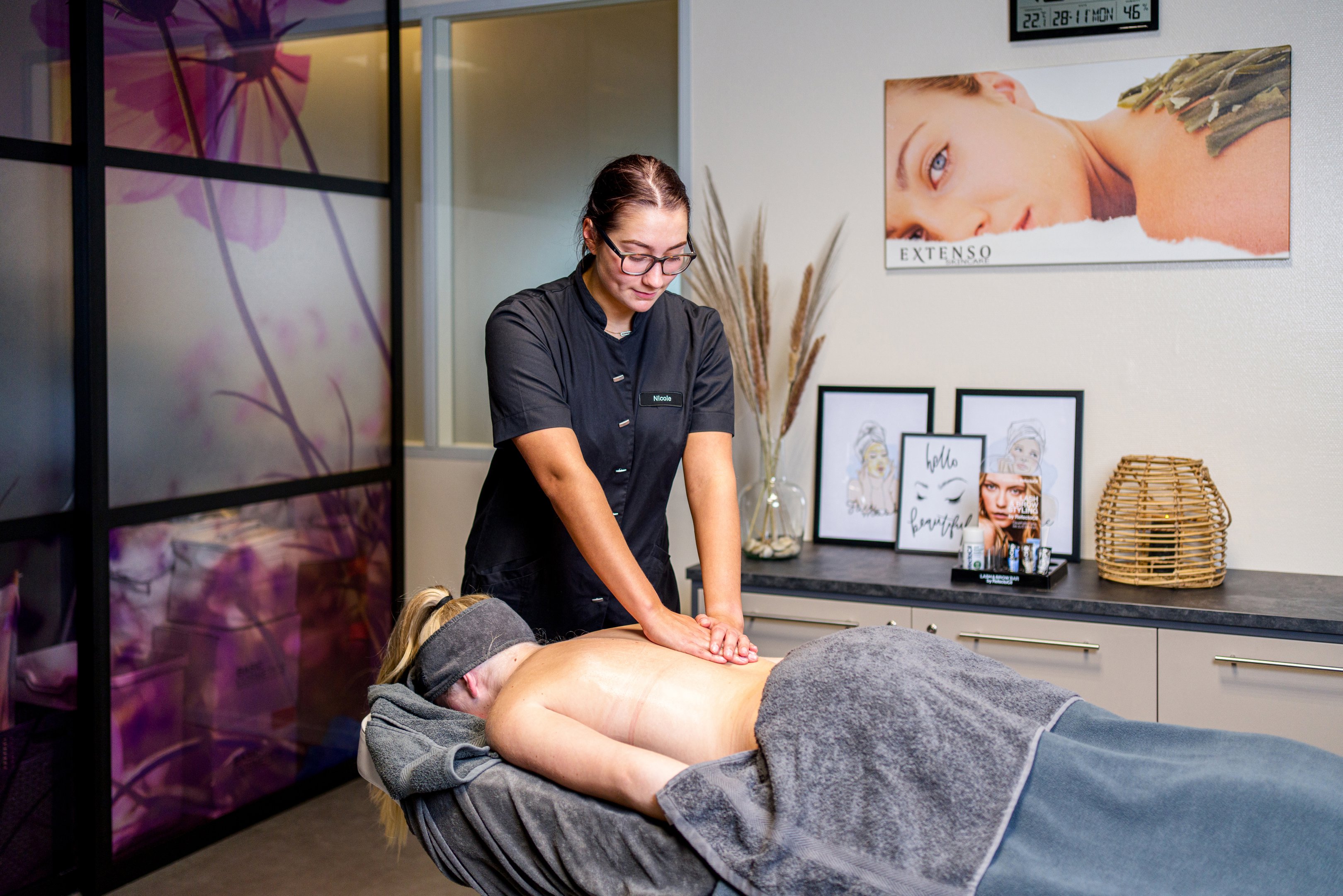 Een docent voert professionele massagetechnieken uit op een student in een praktijkruimte voor volwasseneneducatie.