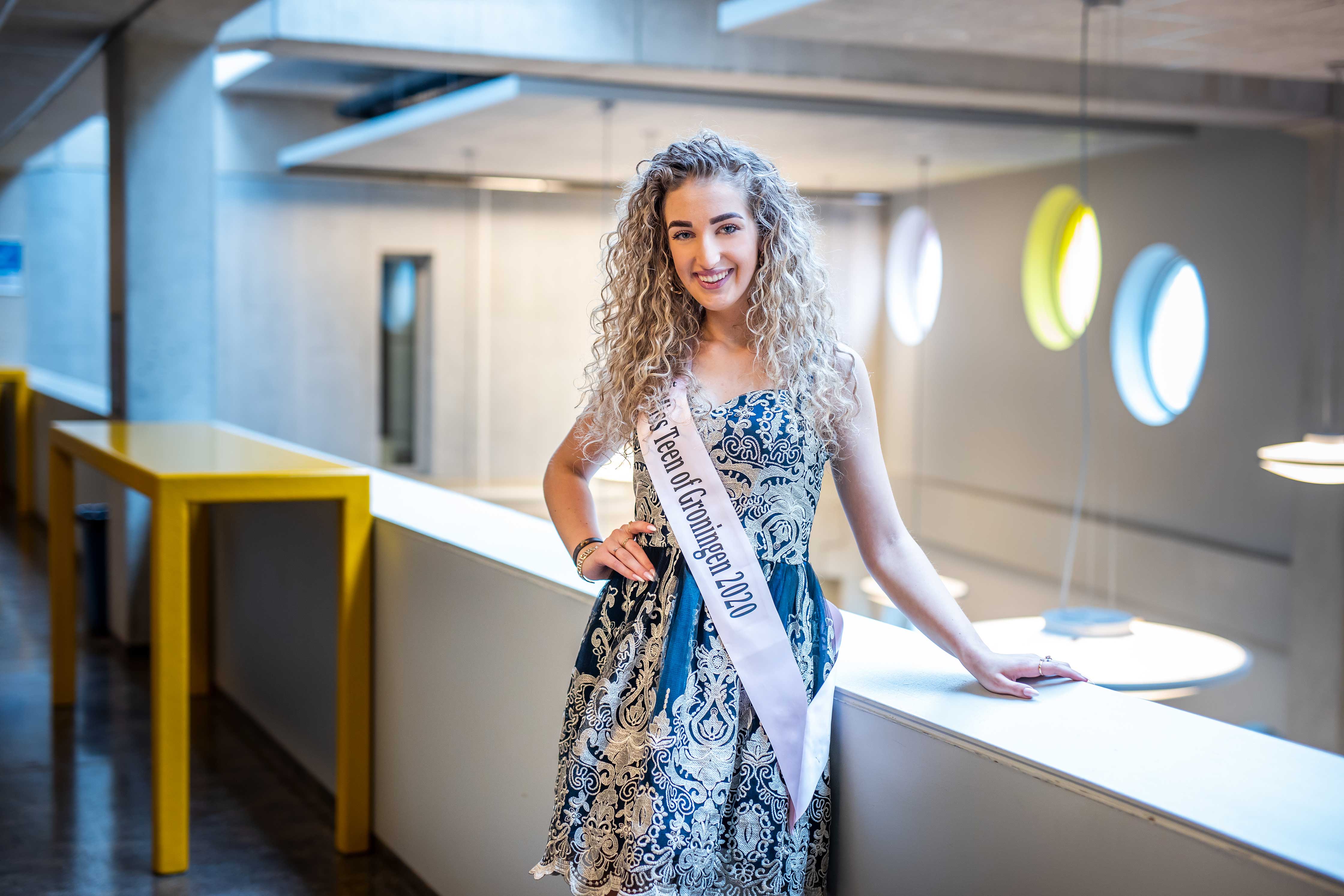 Student en finalist Miss Teen of Groningen 2020 poseert zelfverzekerd in een modern schoolgebouw.
