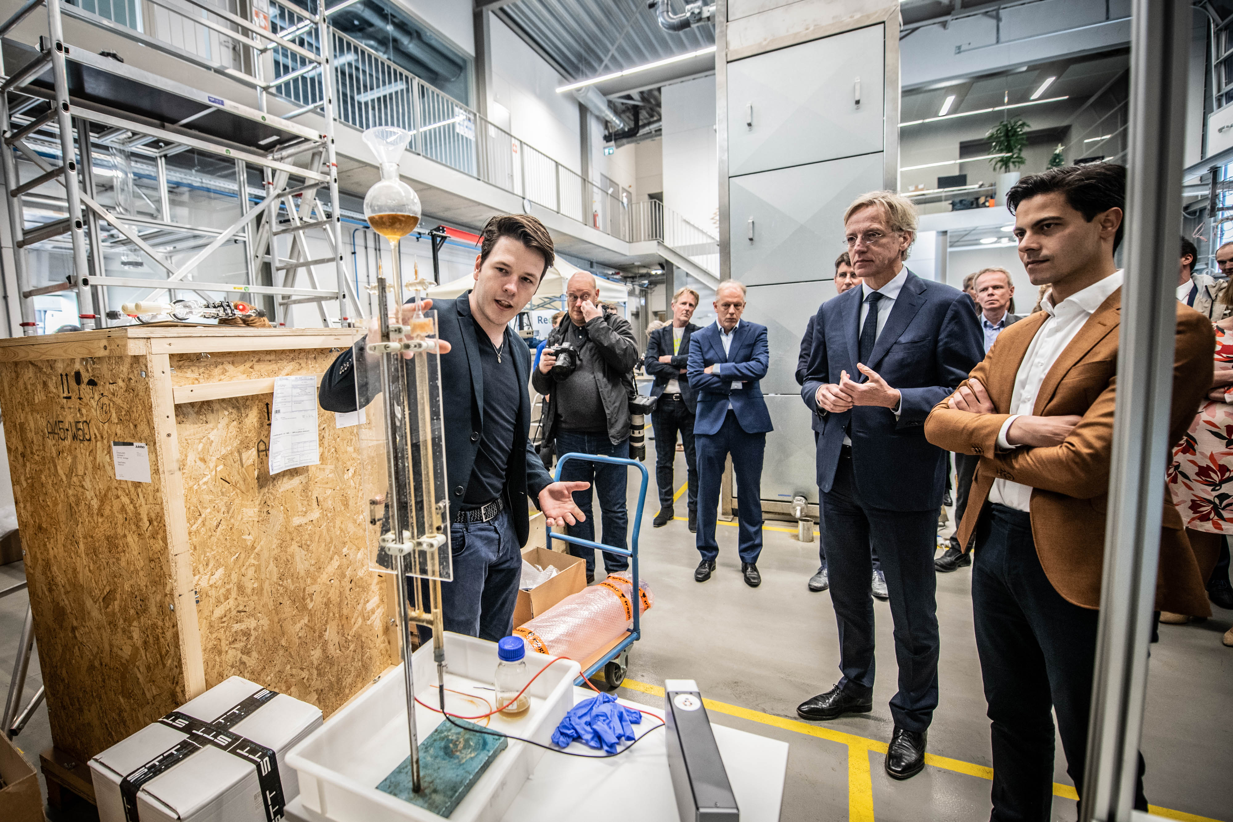 Een student demonstreert een duurzaam onderwijsproject aan Minister Dijkgraaf en andere aanwezigen.