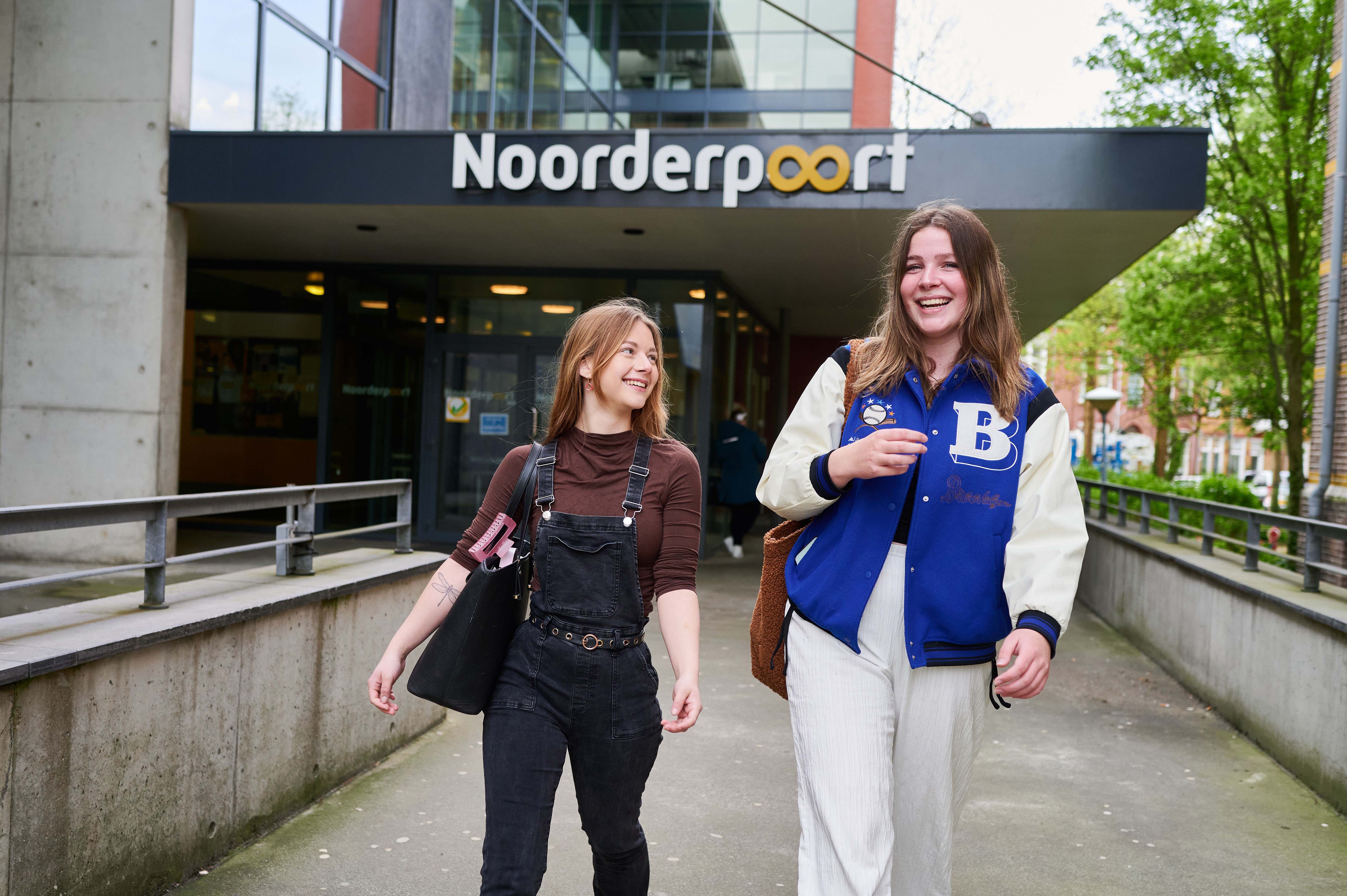 Twee studenten lopen samen voor de ingang van Noorderpoort, een mbo-onderwijsinstelling in Noord-Nederland.
