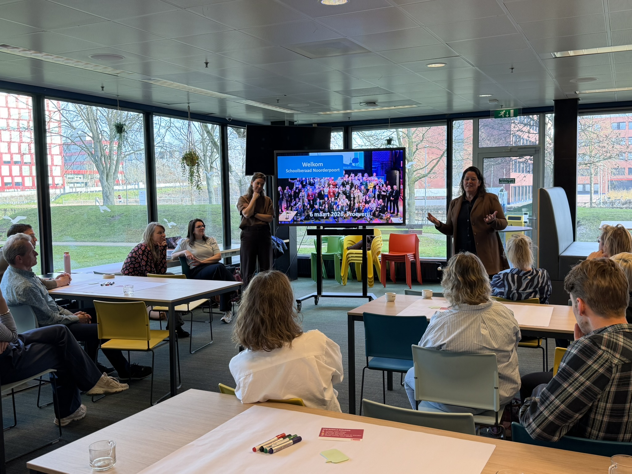 Groep deelnemers zit in een ruimte voor een presentatie tijdens een sessie van Noorderpoort Beraad.