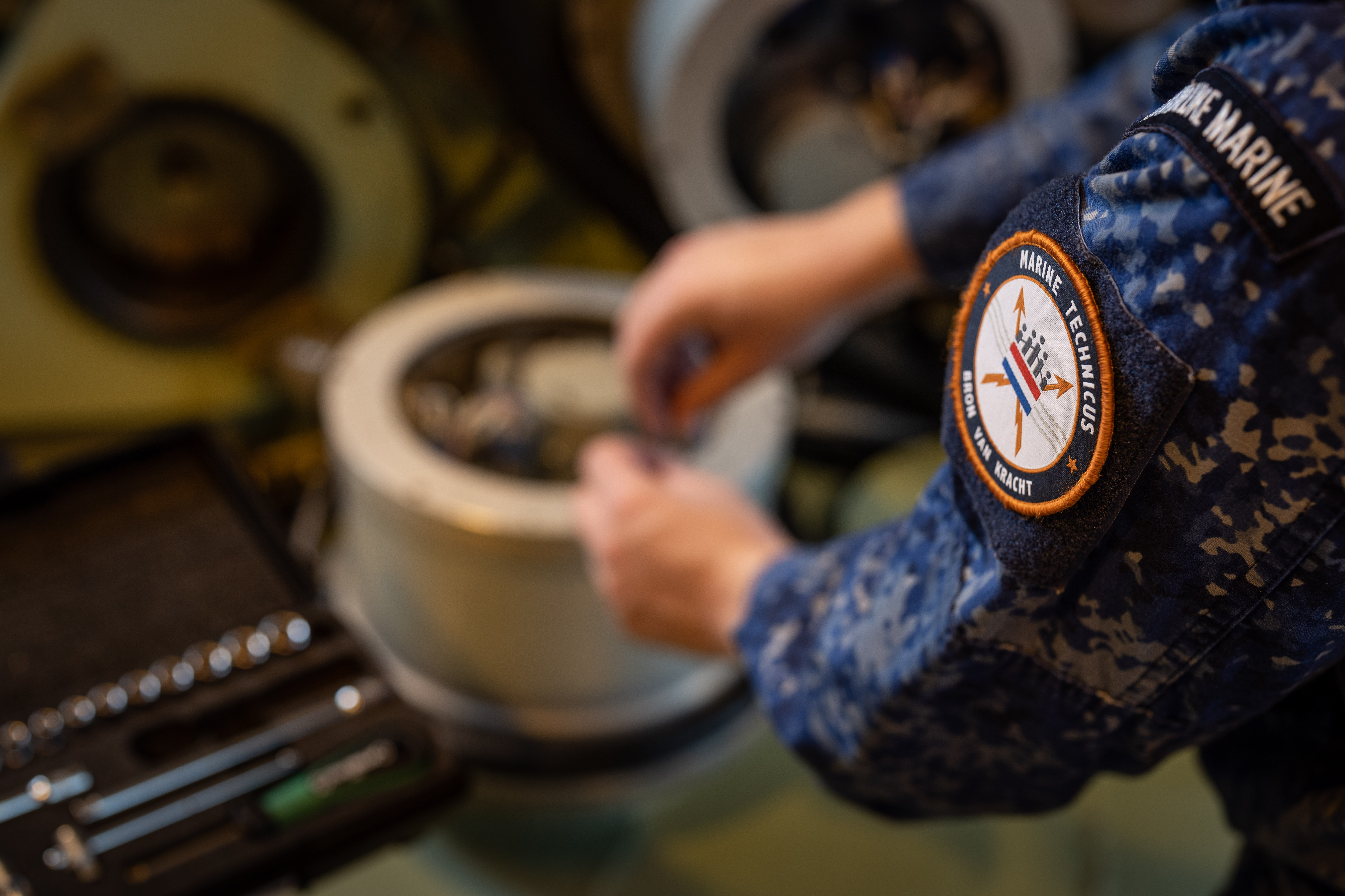 Technisch specialist werkt handmatig aan maritieme apparatuur met gereedschap op de achtergrond