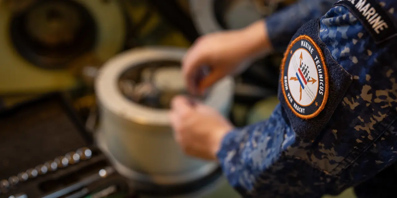 Technisch specialist werkt handmatig aan maritieme apparatuur met gereedschap op de achtergrond