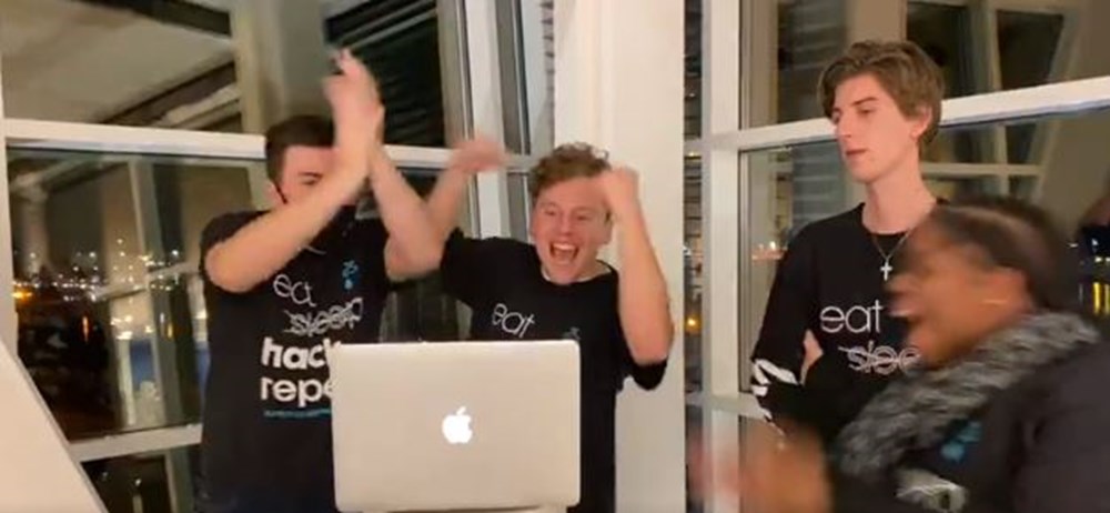 Studenten vieren hun overwinning bij een hackathon over duurzaam drinkwater met een laptop voor zich.