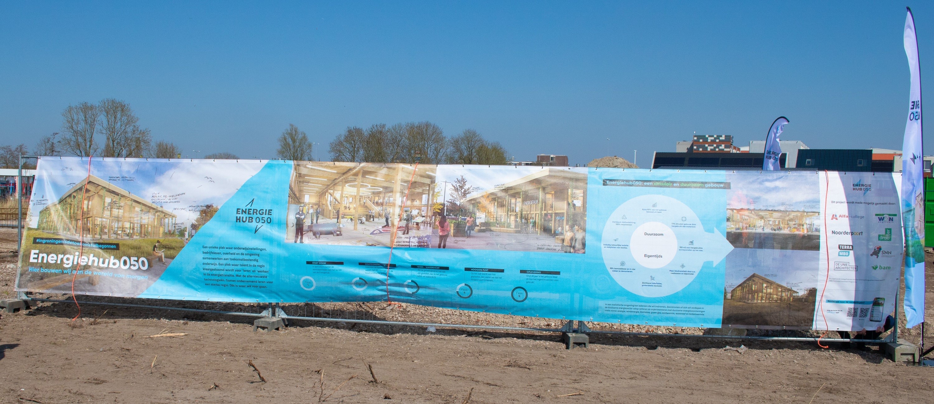 Banner op bouwlocatie toont plannen en informatie over Energiehub050, een duurzaam energieproject in Groningen.