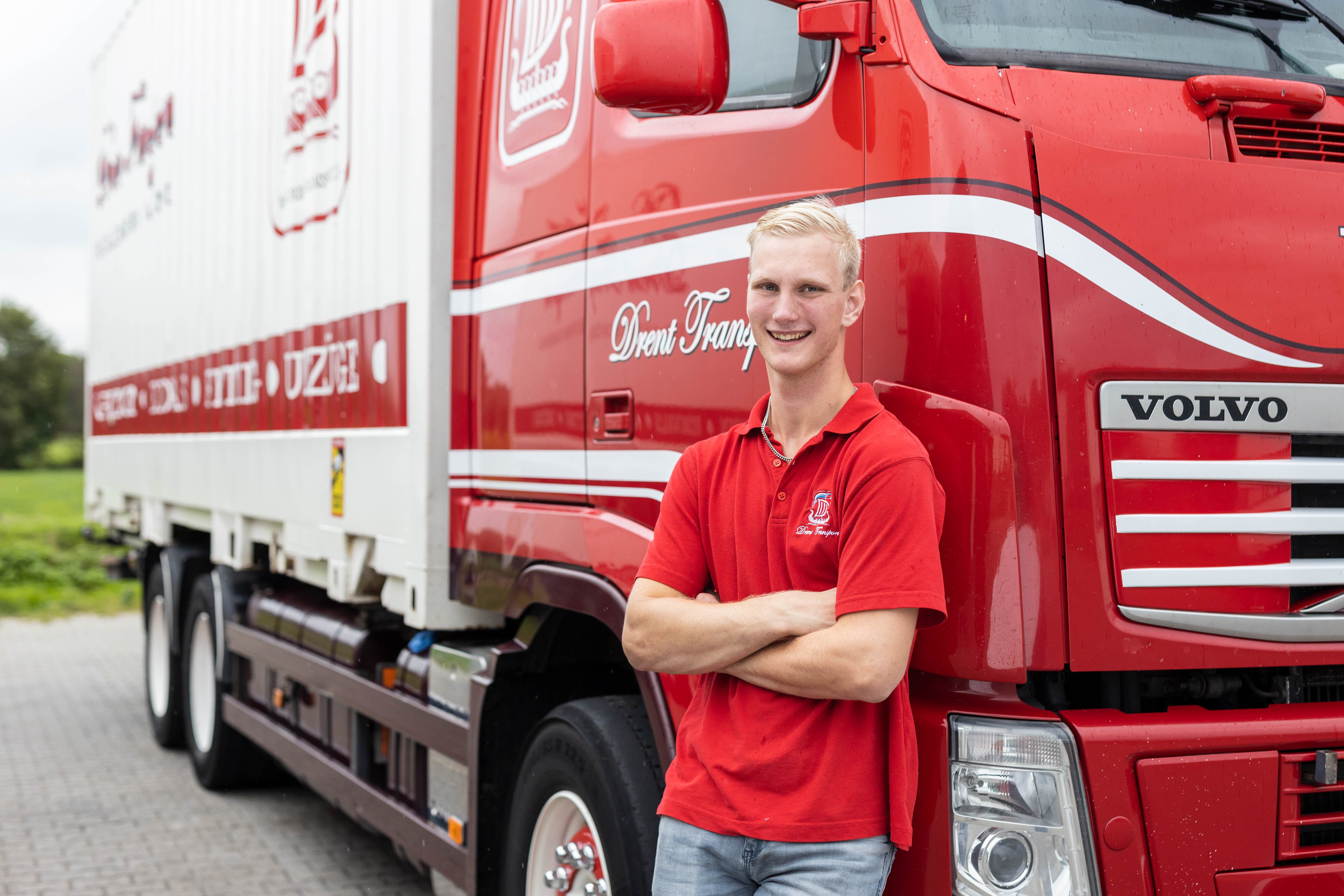 Student staat met armen over elkaar voor een rode vrachtwagen van Noorderpoort, als voorbeeld van praktijkgericht leren