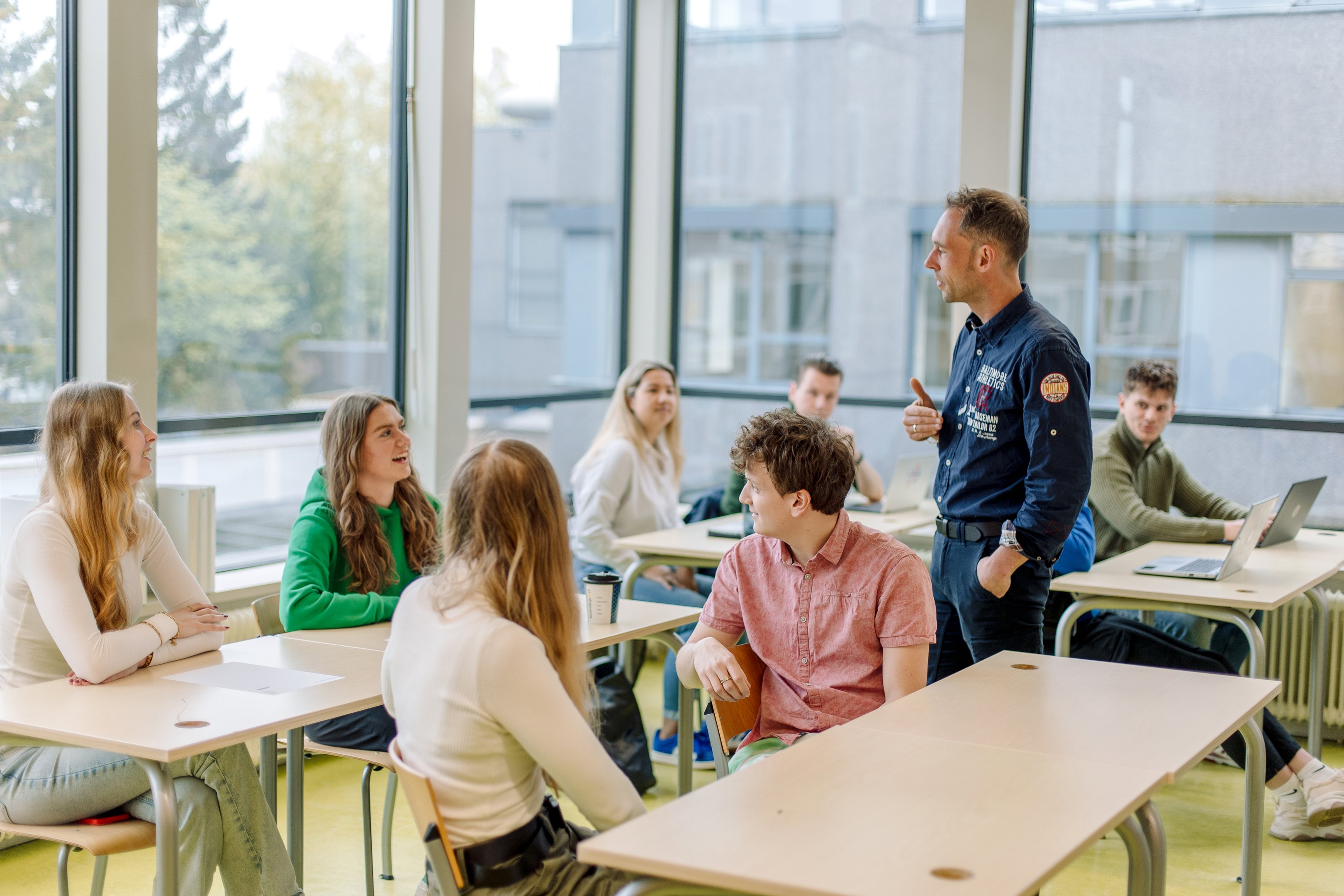 Docent begeleidt een groep studenten tijdens een interactieve les binnen een moderne onderwijsomgeving