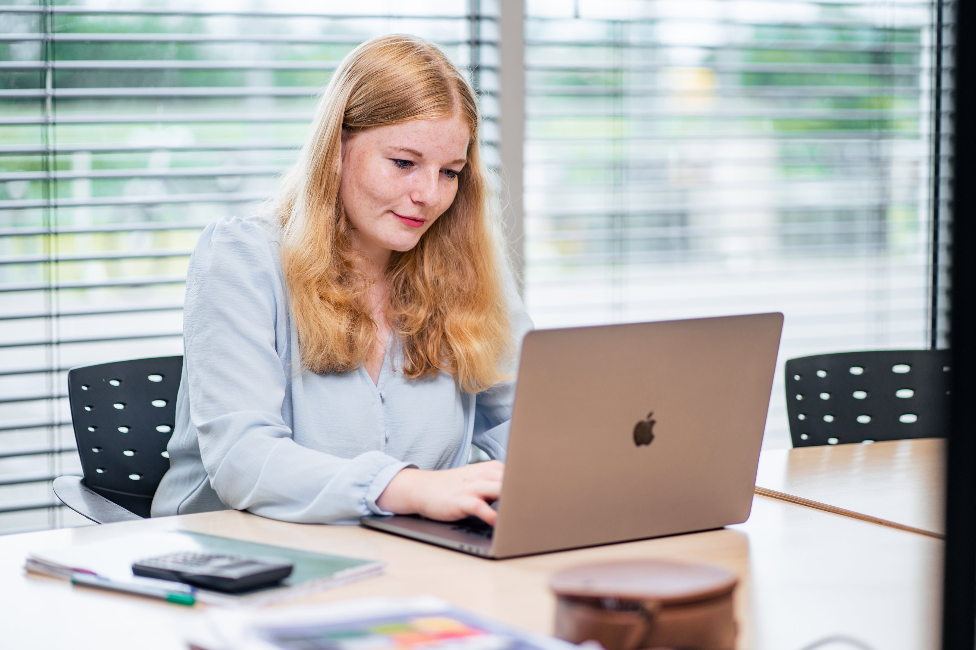 Medewerker werkt geconcentreerd op laptop aan maatwerkproject, passend bij bedrijfsgerichte opleidingen.