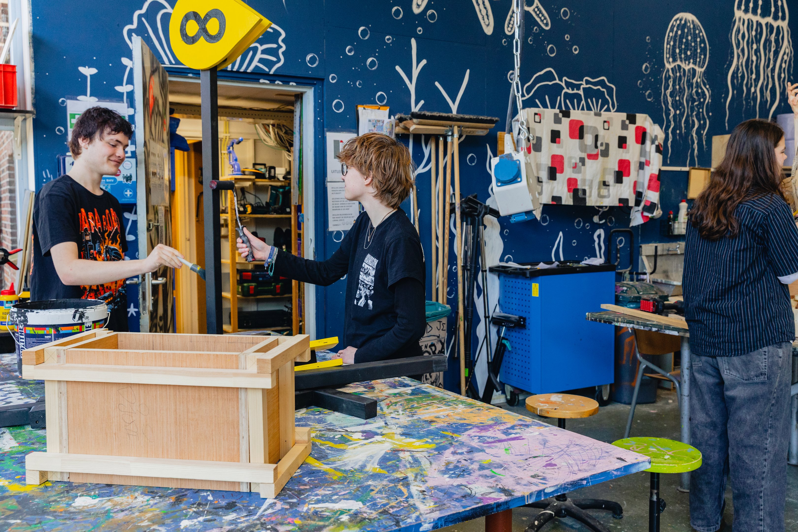 Studenten werken samen in een creatieve werkplaats aan ruimtelijke vormgeving projecten.