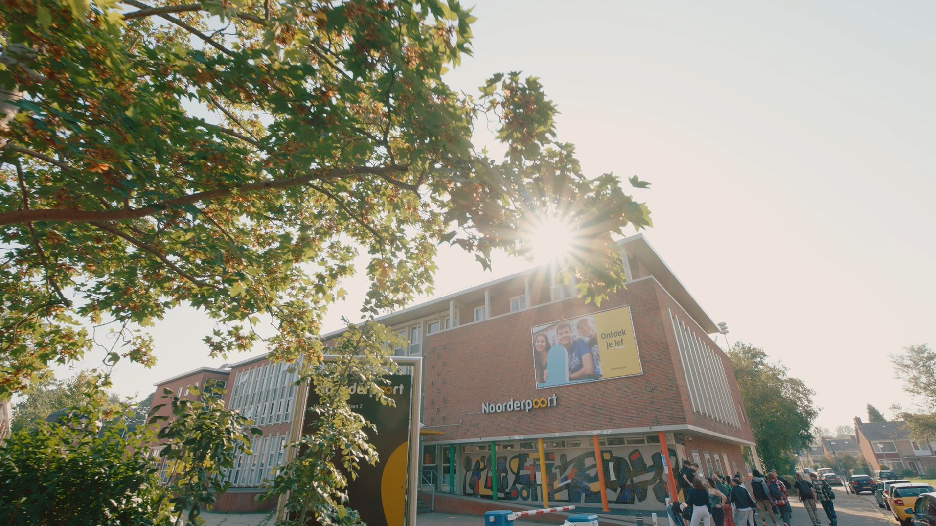 Het onderwijsgebouw Noorderpoort aan Verzetsstrijderslaan 2 in Groningen, met studenten bij de ingang.
