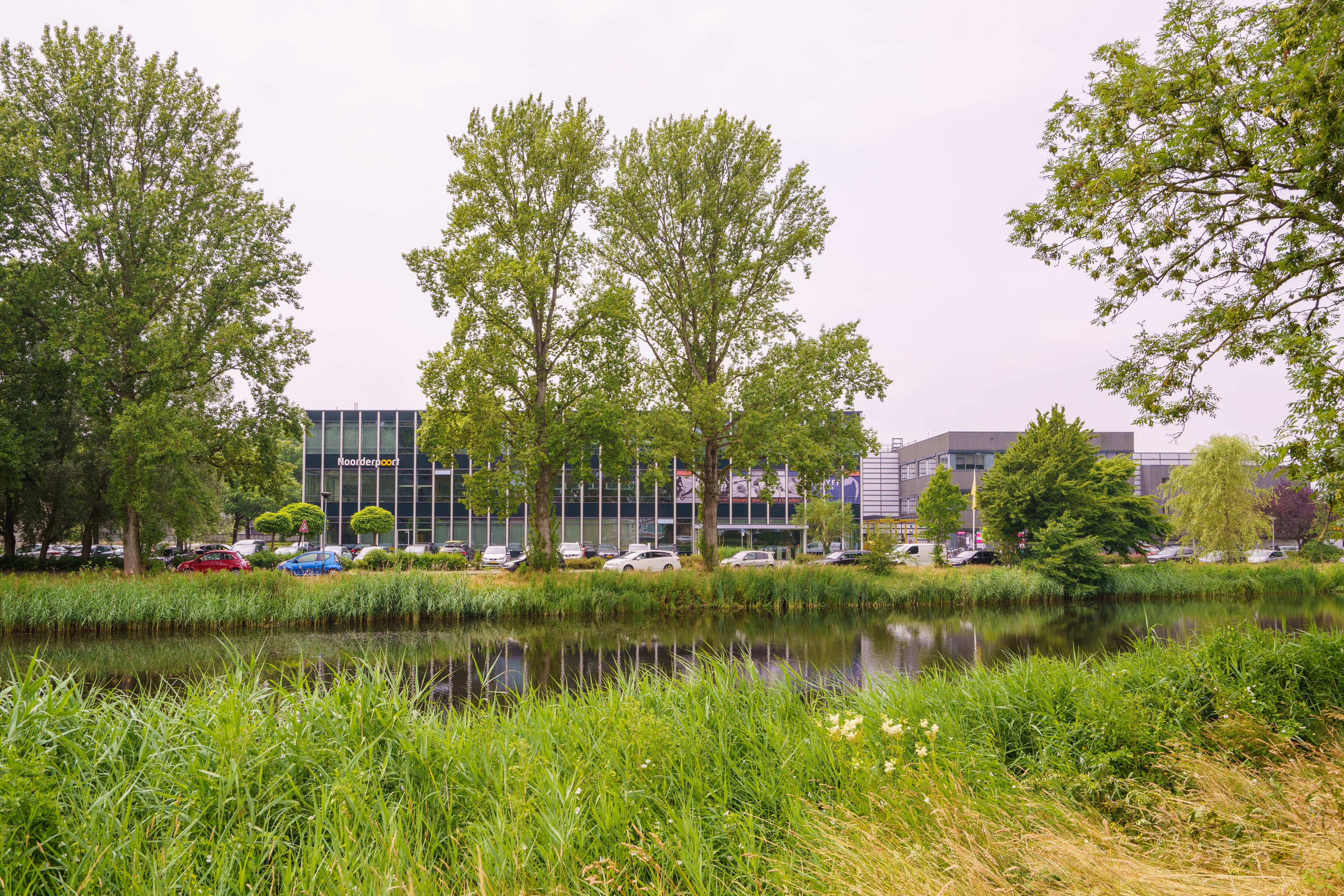 Moderne schoolgebouwen van Noorderpoort aan de Hora Siccamasingel in Groningen met waterpartij op de voorgrond