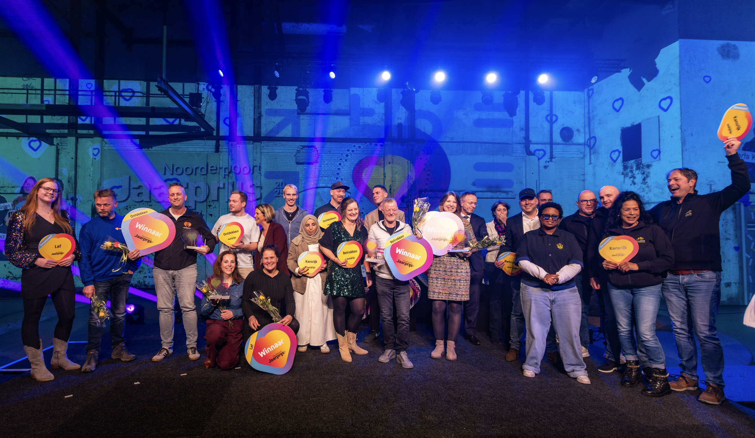 Winnaars en genomineerden van de Noorderpoort Jaarprijs 2025 verzamelen op het podium met prijzen in handen.