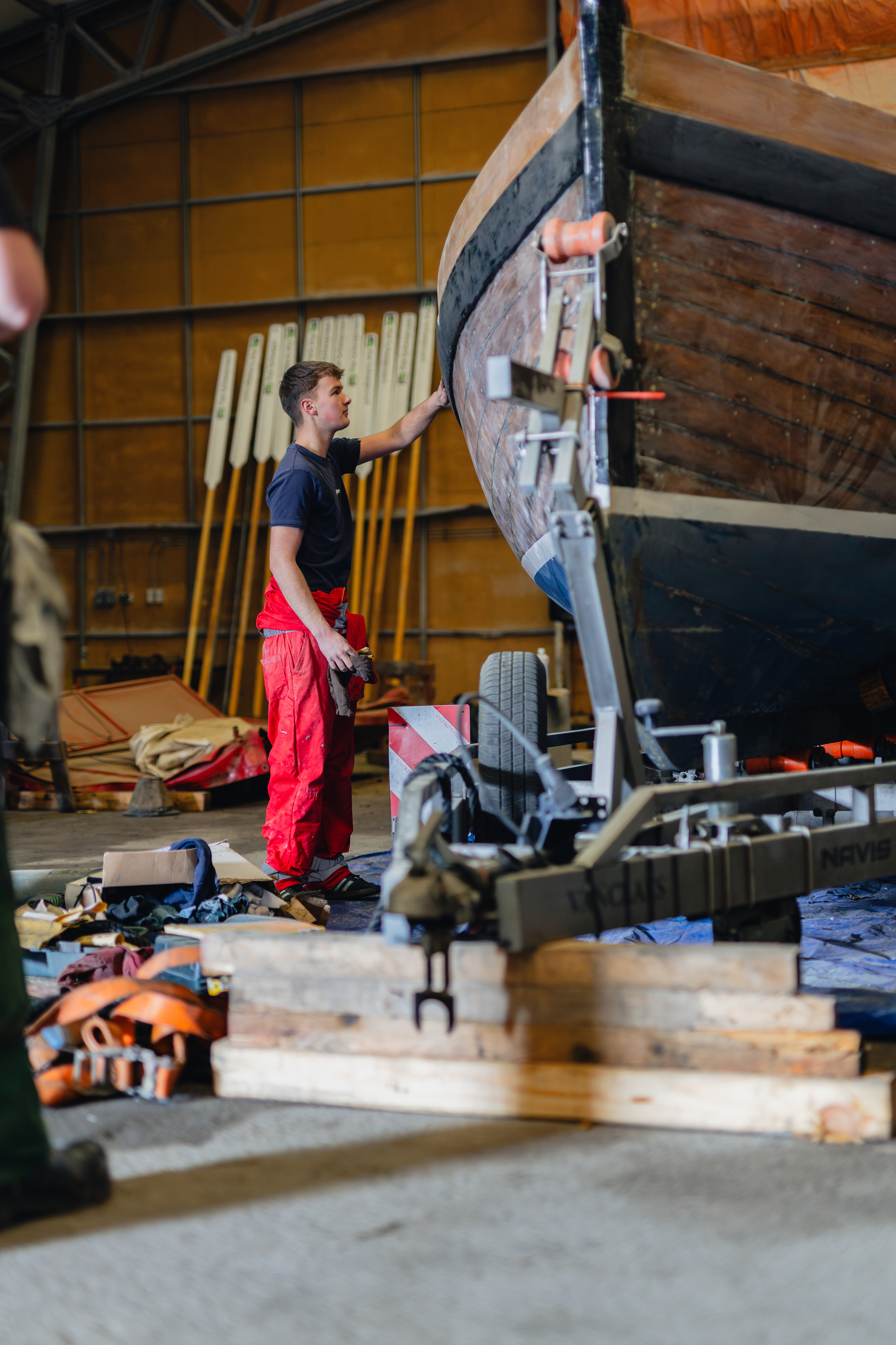 Maritiem student inspecteert een houten boot in een werkplaats van Noorderpoort