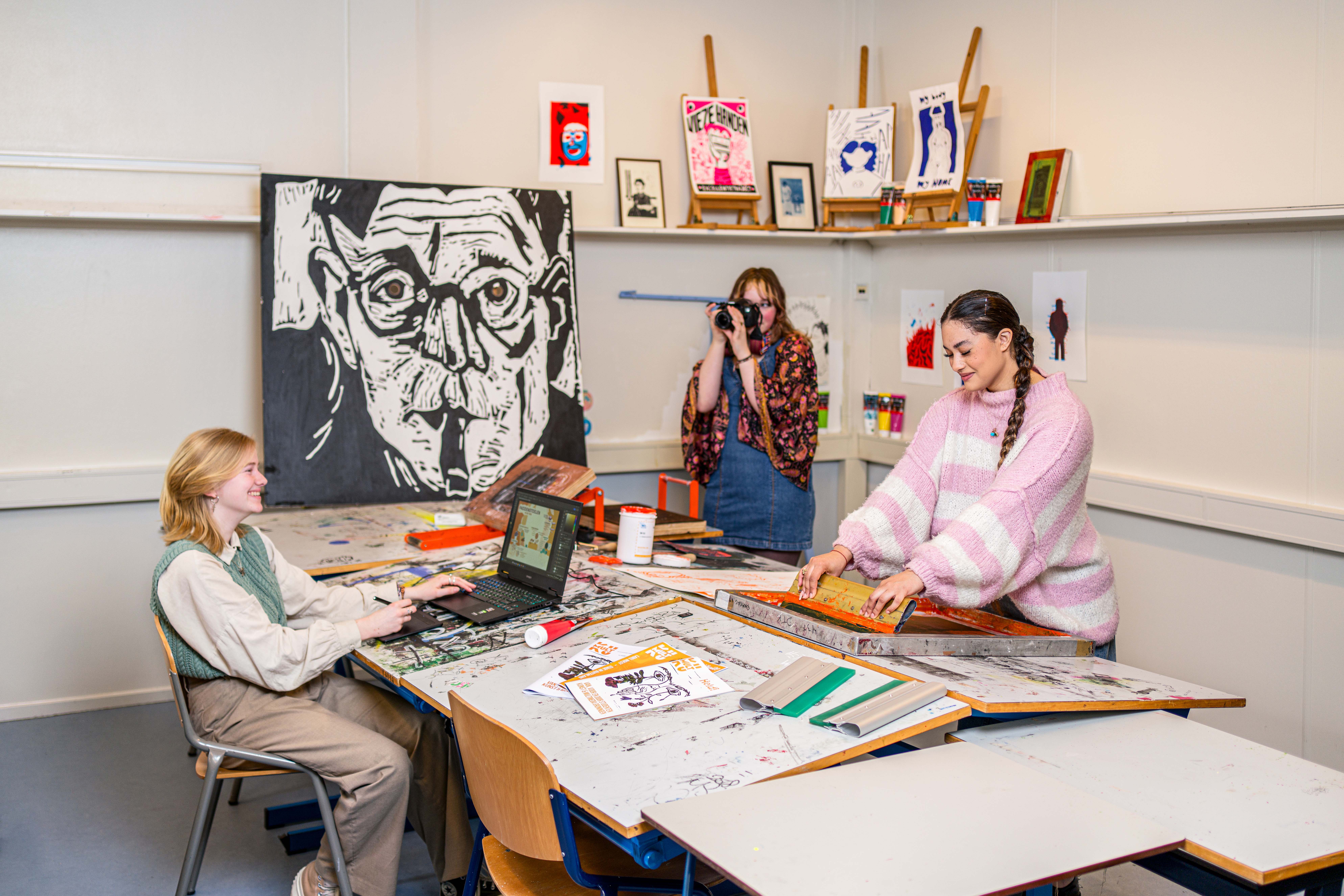 Noorderpoort-studenten werken samen aan creatieve projecten in een praktijklokaal met eigen kunstwerken.