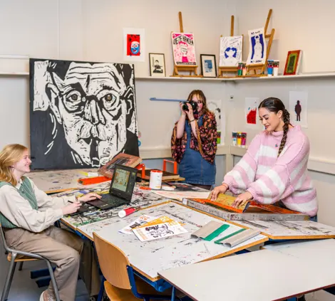 Noorderpoort-studenten werken samen aan creatieve projecten in een praktijklokaal met eigen kunstwerken.