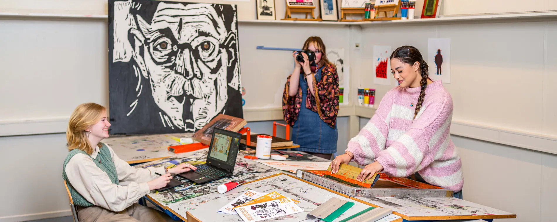 Noorderpoort-studenten werken samen aan creatieve projecten in een praktijklokaal met eigen kunstwerken.