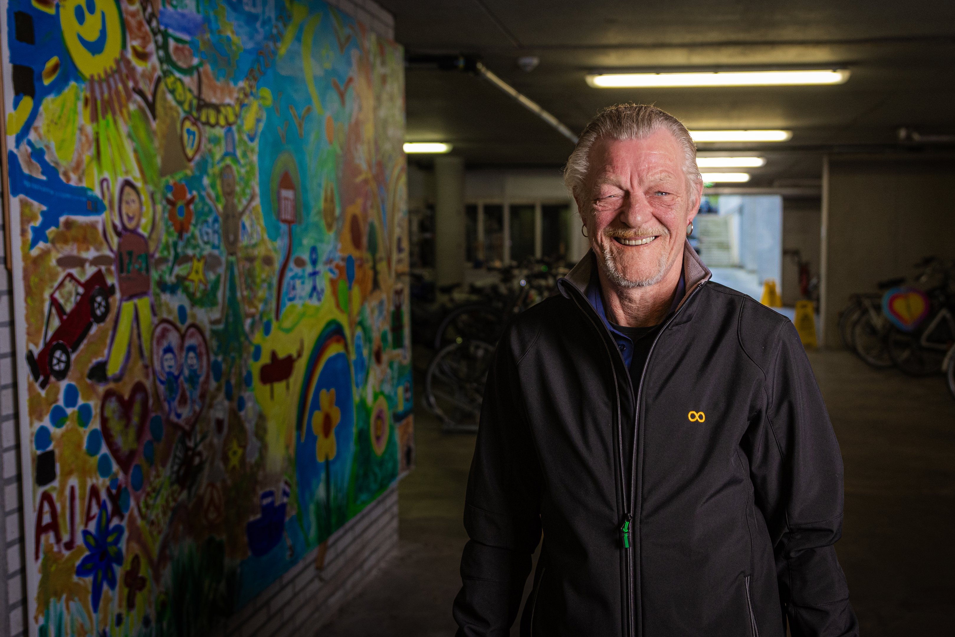 Persoon staat in parkeergarage met kleurrijke muurschildering op de achtergrond