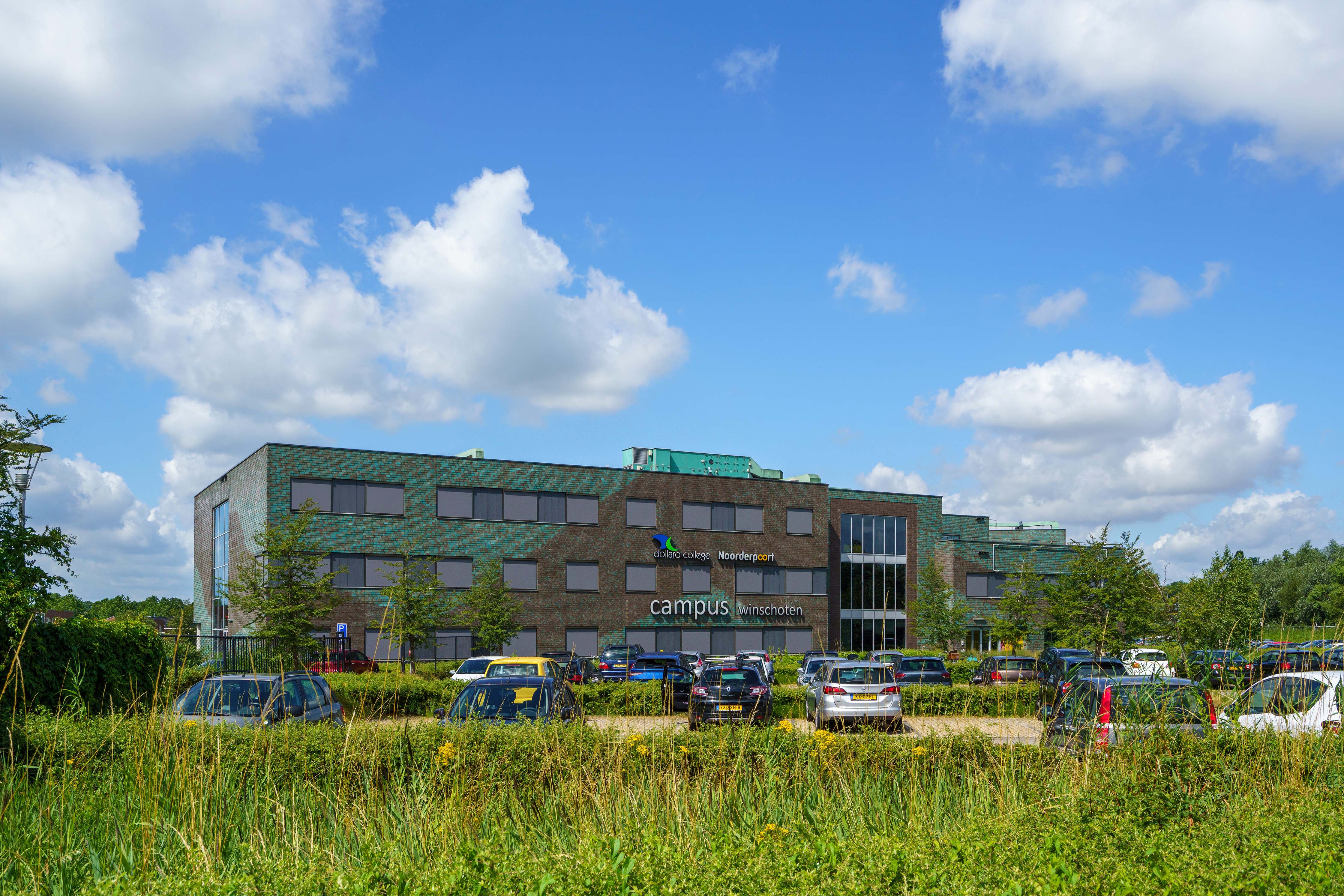 Gebouw van Noorderpoort campus Pc Hooftlaan in Winschoten met parkende auto's rondom